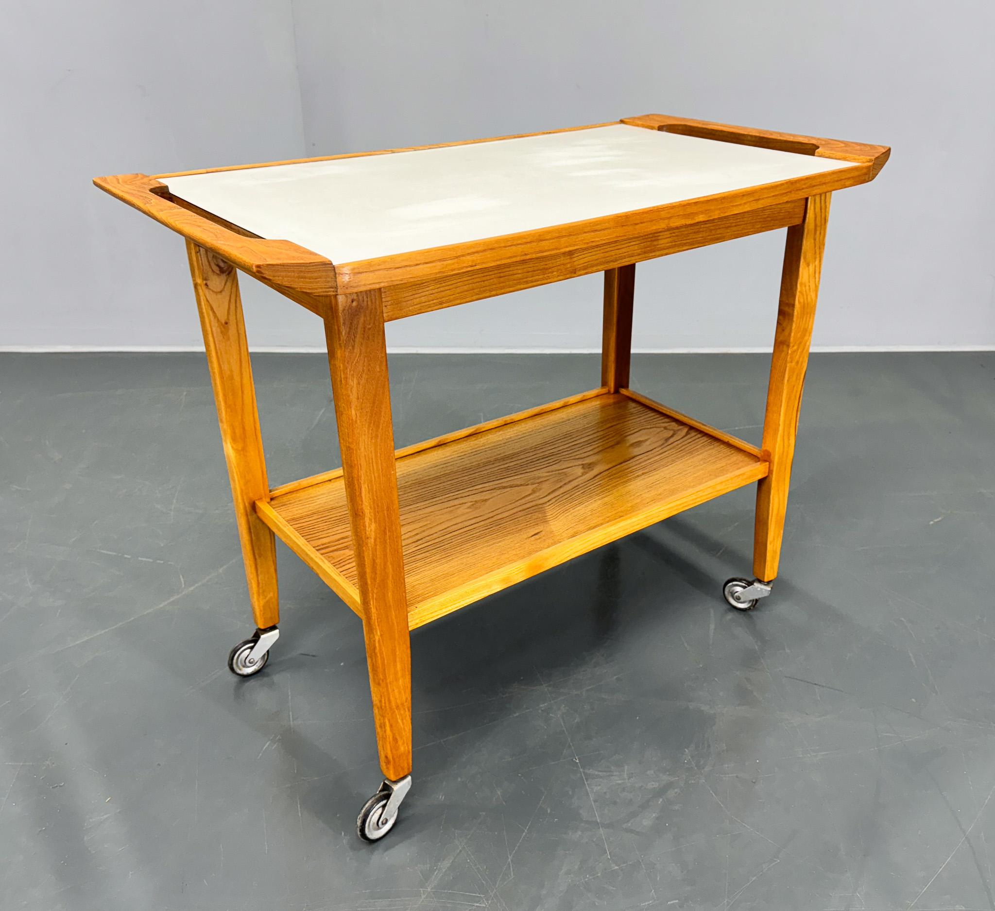 Table de service ou table d'appoint sur roulettes du milieu du siècle dernier, en bois avec plateau en contreplaqué. Bon état d'origine avec quelques signes d'utilisation (voir photo).