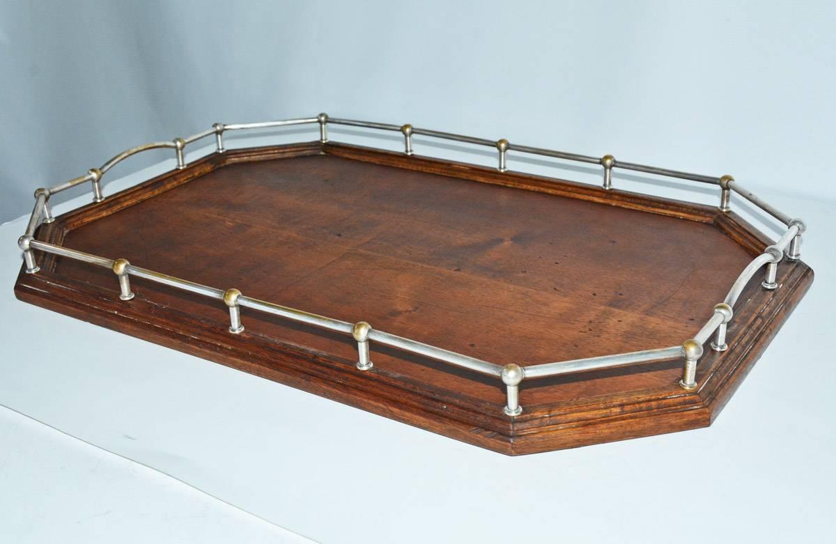 Vintage 1910s-1950s English wood and chrome serving tray with flat ball feet, chrome side gallery rails, and center accent shield/placard. Condition: some wear. Materials: wood/chrome. No maker's mark
English traditional.