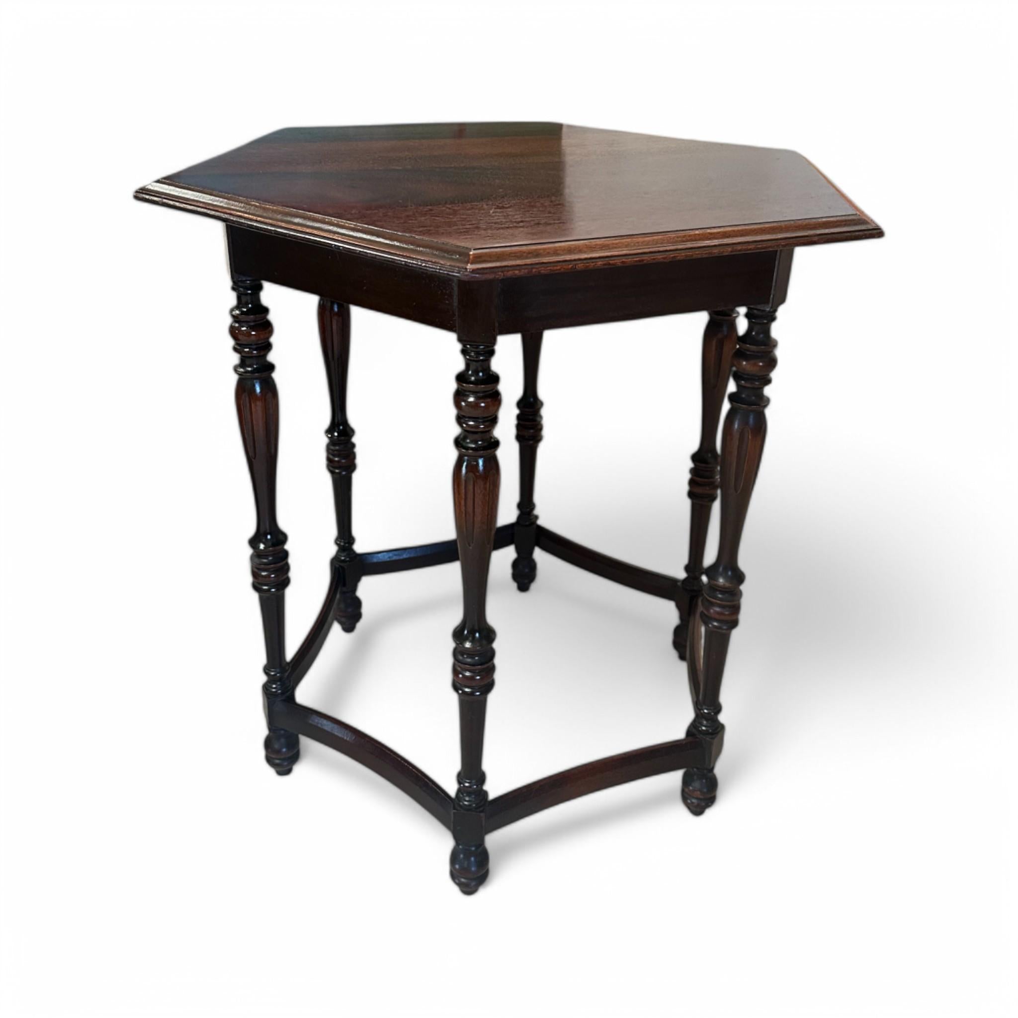 Cette table d'appoint Vintage présente un plateau hexagonal remarquable et des pieds joliment tournés, offrant un caractère intemporel avec une touche de charme du Vieux Monde. Sa finition en bois riche et sa base sculpturale en font une pièce