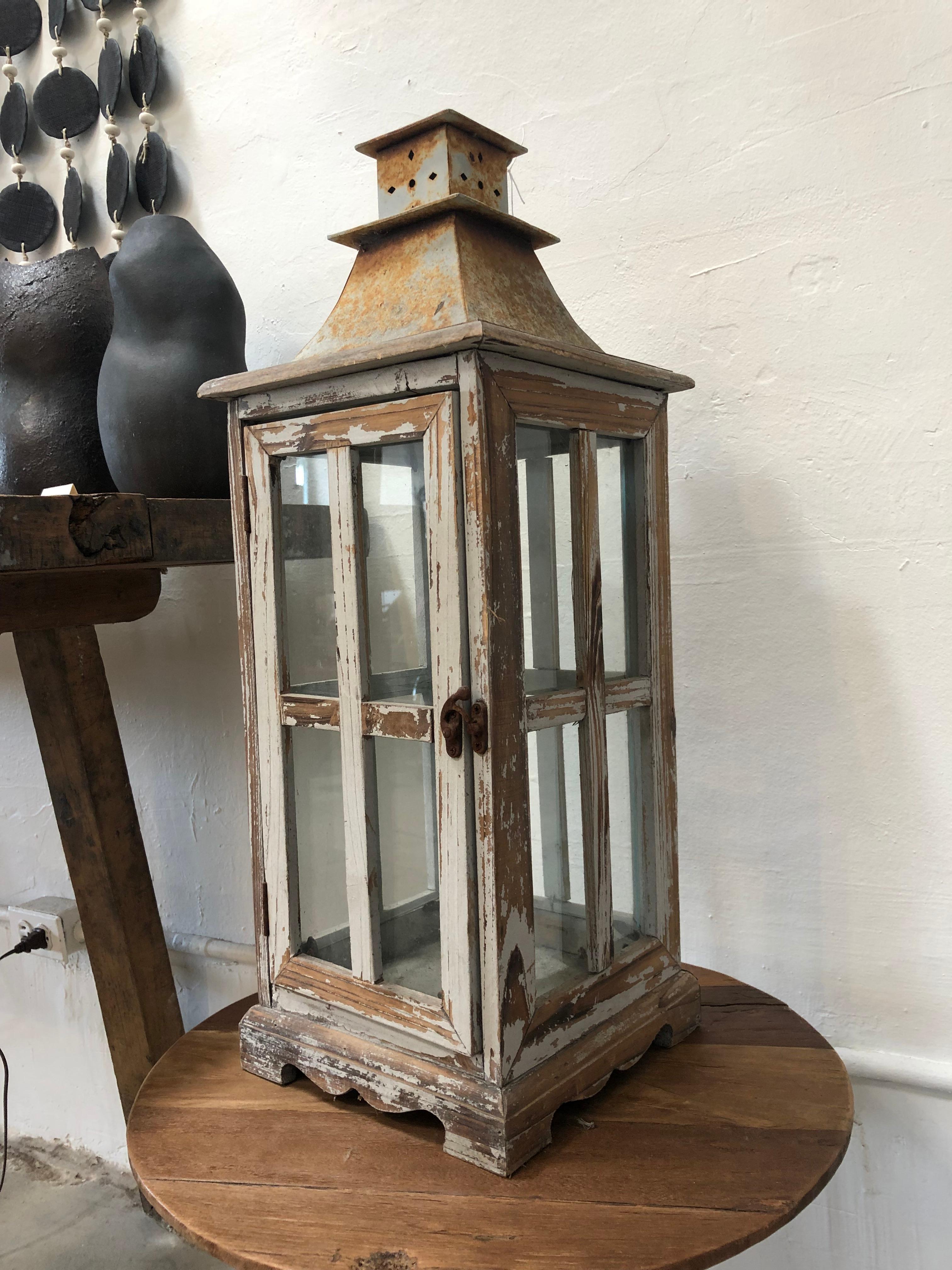 This vintage wood large Lantern has lots of charm due to the wear from its age. Featuring wood and metal, this lantern can be used outdoors or in an entryway. It has a hook lock as well which is still in working condition. Place a candle inside and