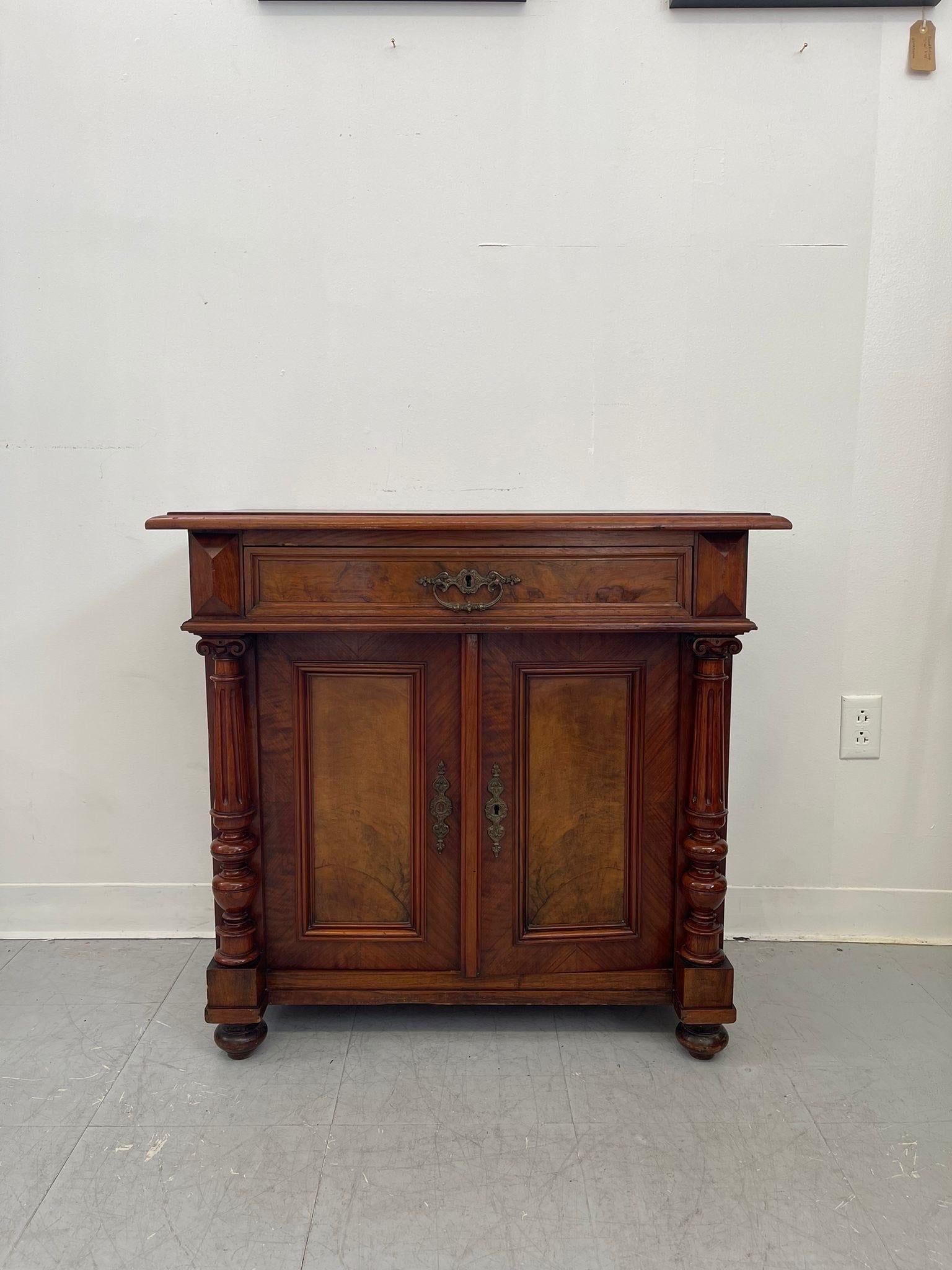 This side table with single dovetailed drawer above two door cabinet space. Carved wood detailing. Original hardware. Front two legs are tuned wood and has a unique shape. Vintage Condition Consistent with Age as Pictured.

Dimensions. 32 W ; 18 D ;