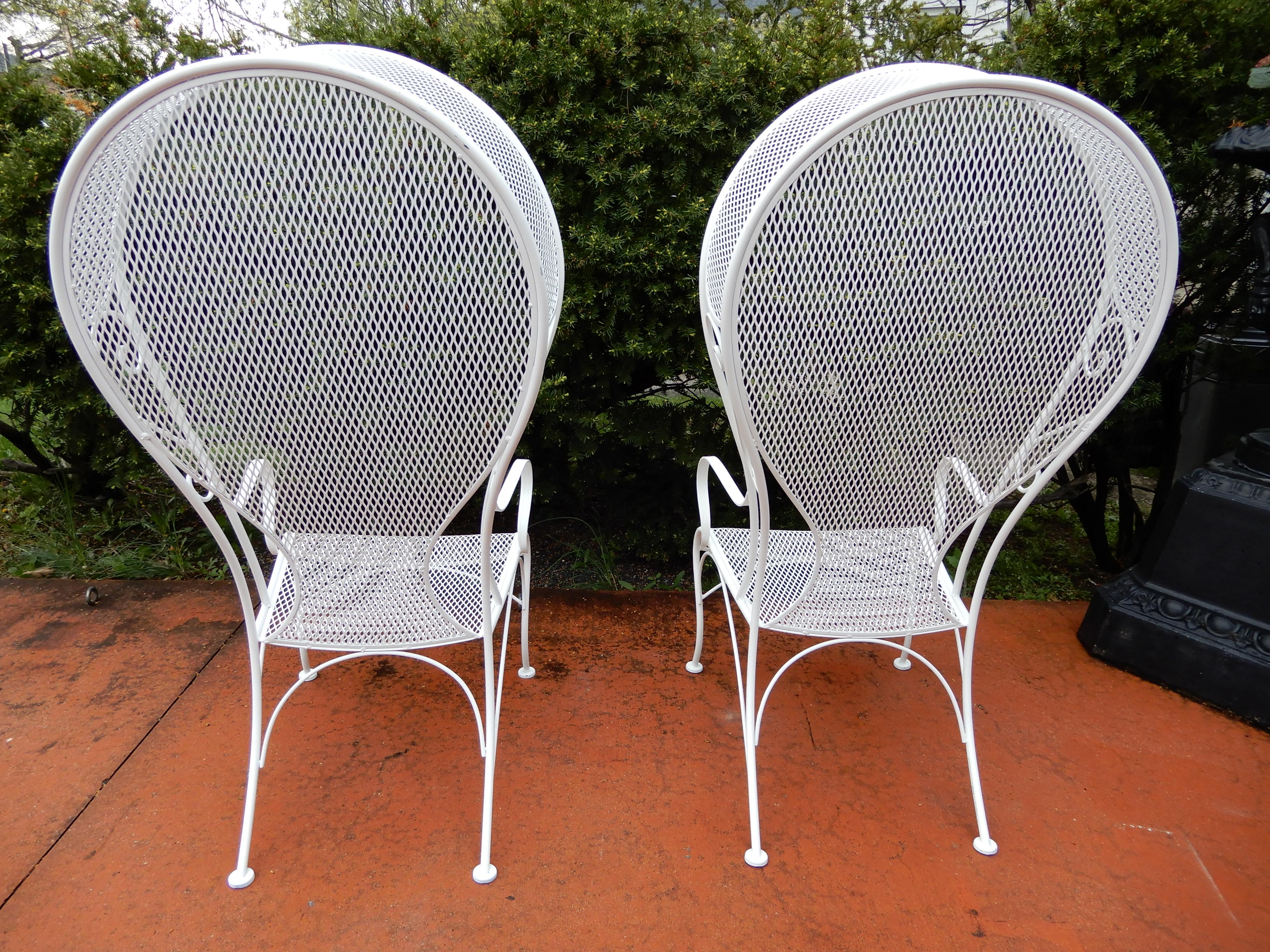 A pair of vintage Woodard hooded wrought iron chairs. The chairs have just been painted white and are in excellent condition. Other vintage Woodard Hollywood Regency wrought iron furniture is available. Let me know if I can assist with shipping