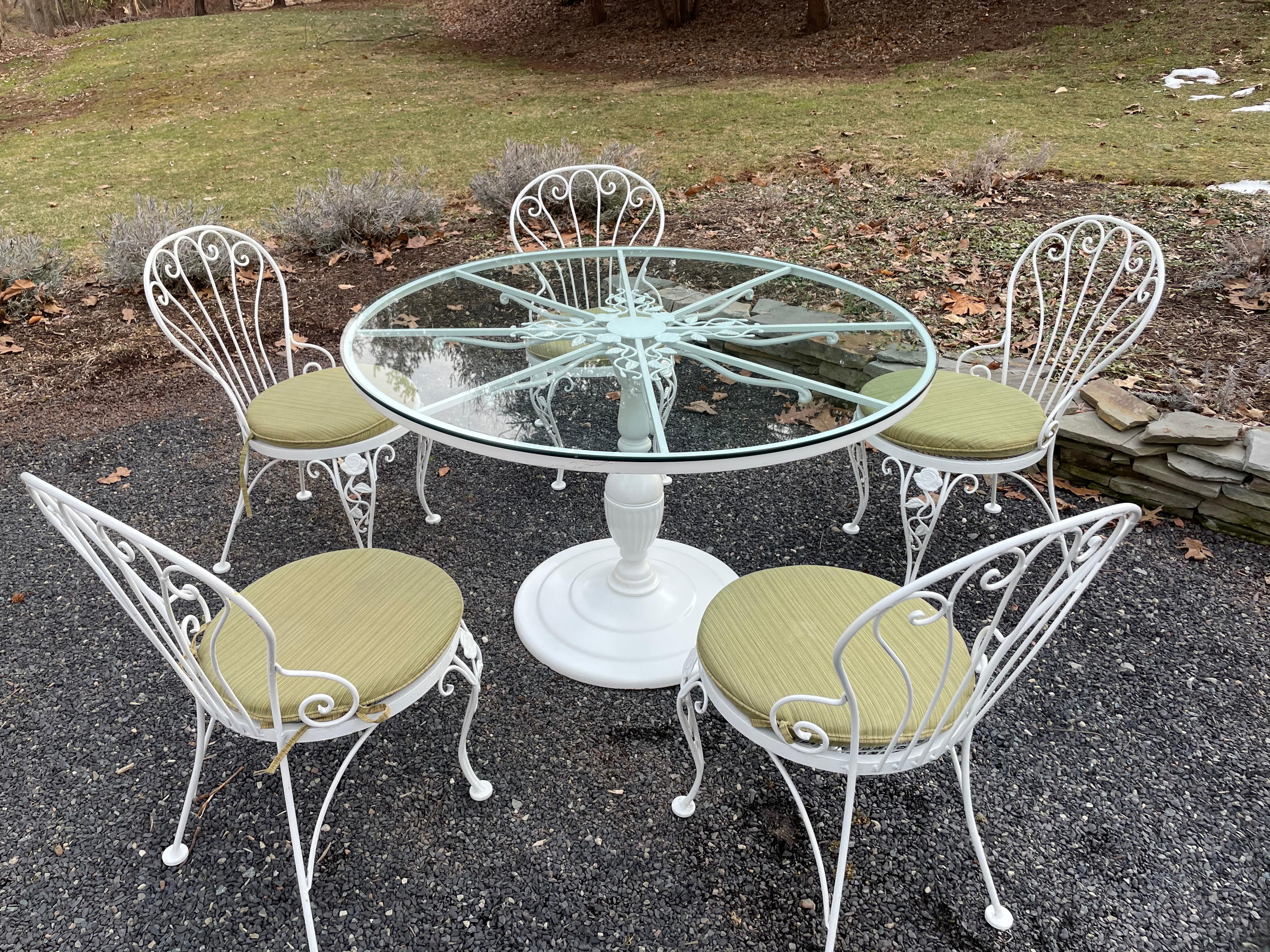 Classic patio dining table and chairs by Woodard having round table with center pedestal and pretty flower and leaf motife. Table includes 3/8