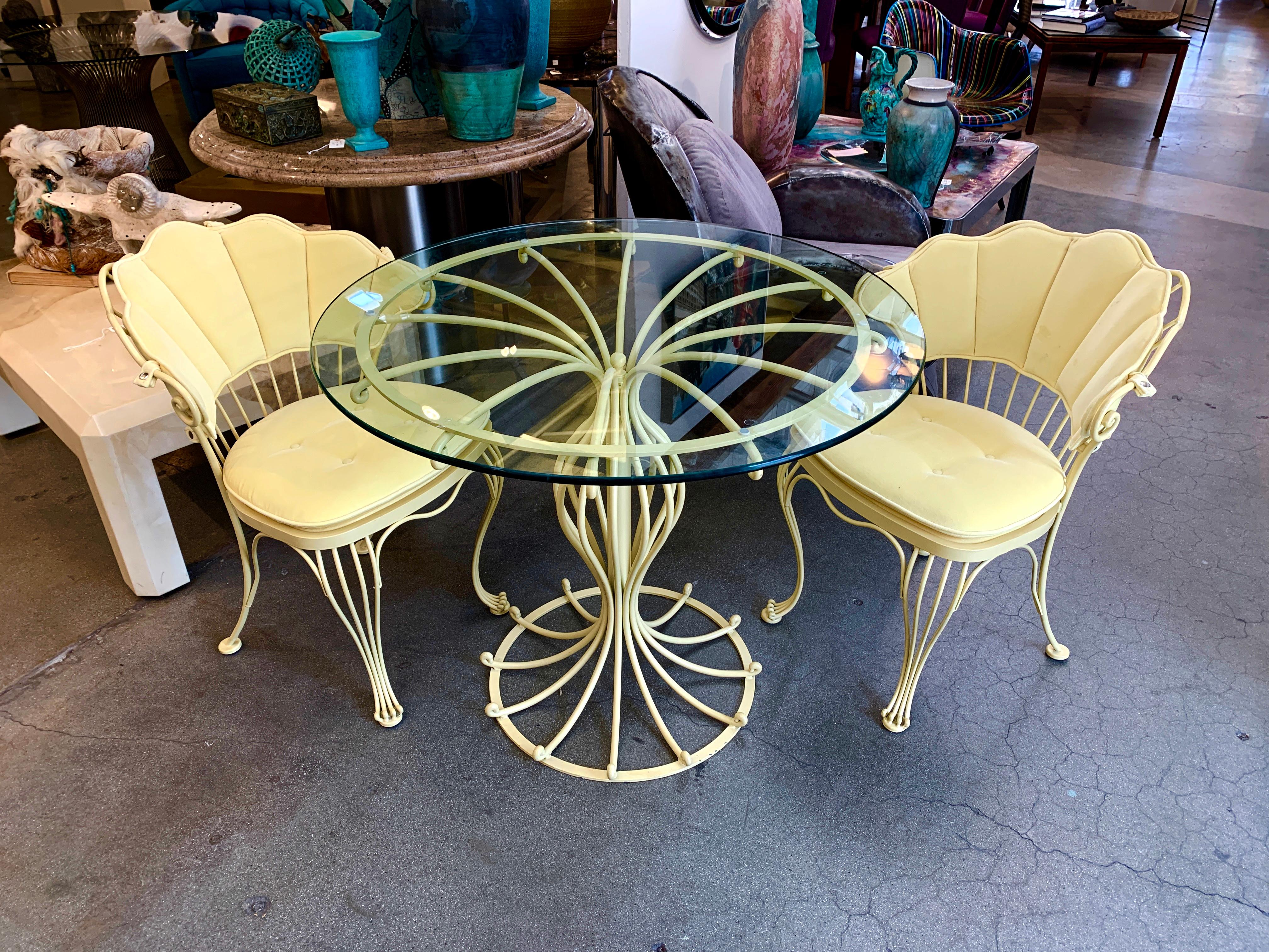A wonderful wrought iron set by Woodard. It has been painted a lovely shade of yellow and the seat cushions and backs down in a pretty cotton velvet. Some losses to the paint finish and minor marks to the glass top. Chairs measure 31.5 inches tall,