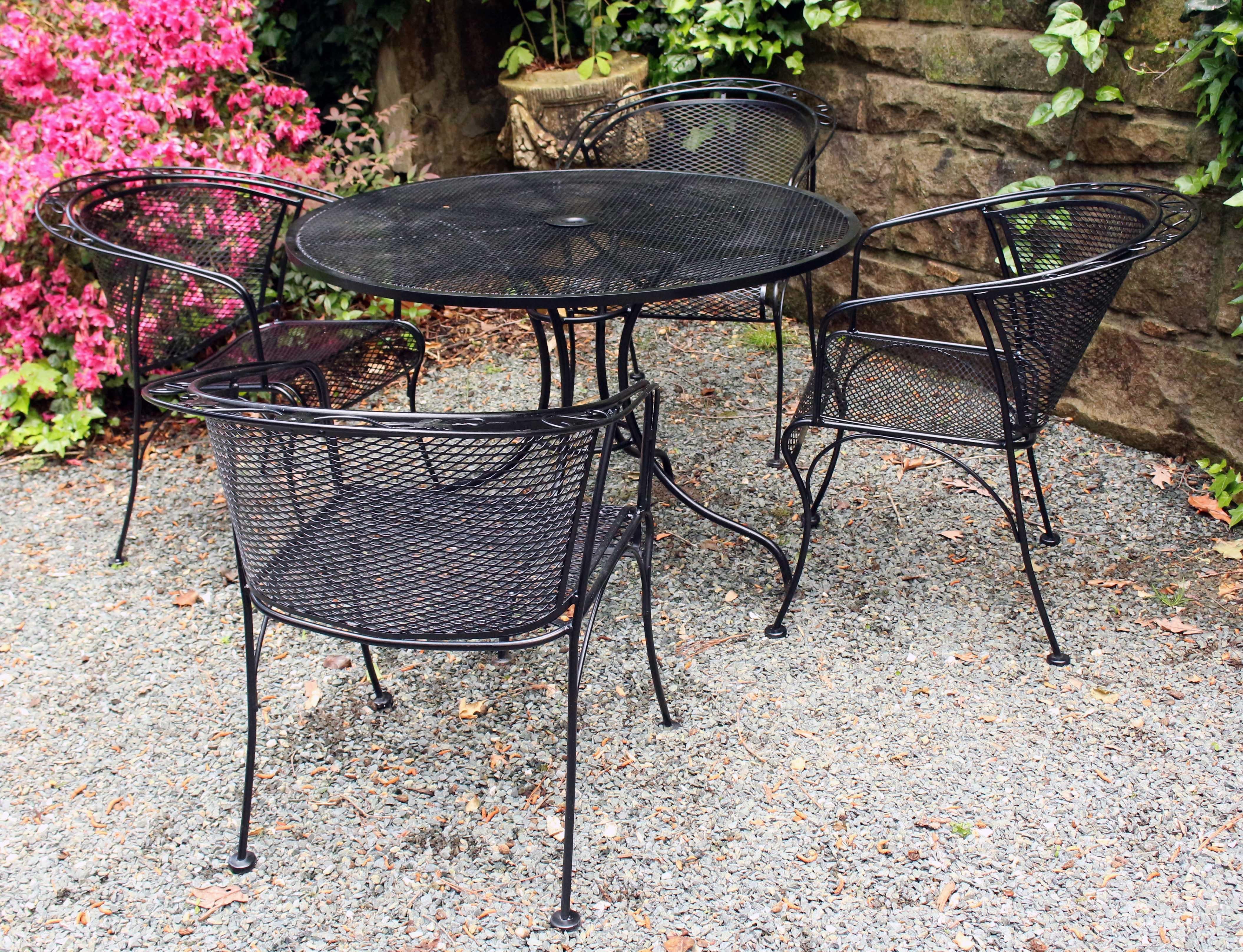 Vintage Woodard wrought iron round table & 4 barrel back arm chairs. Best quality stretchered table. Chairs with central flower to trailing vine & leaf motif. Original black paint brushed & repainted.

Table: 42 1/2
