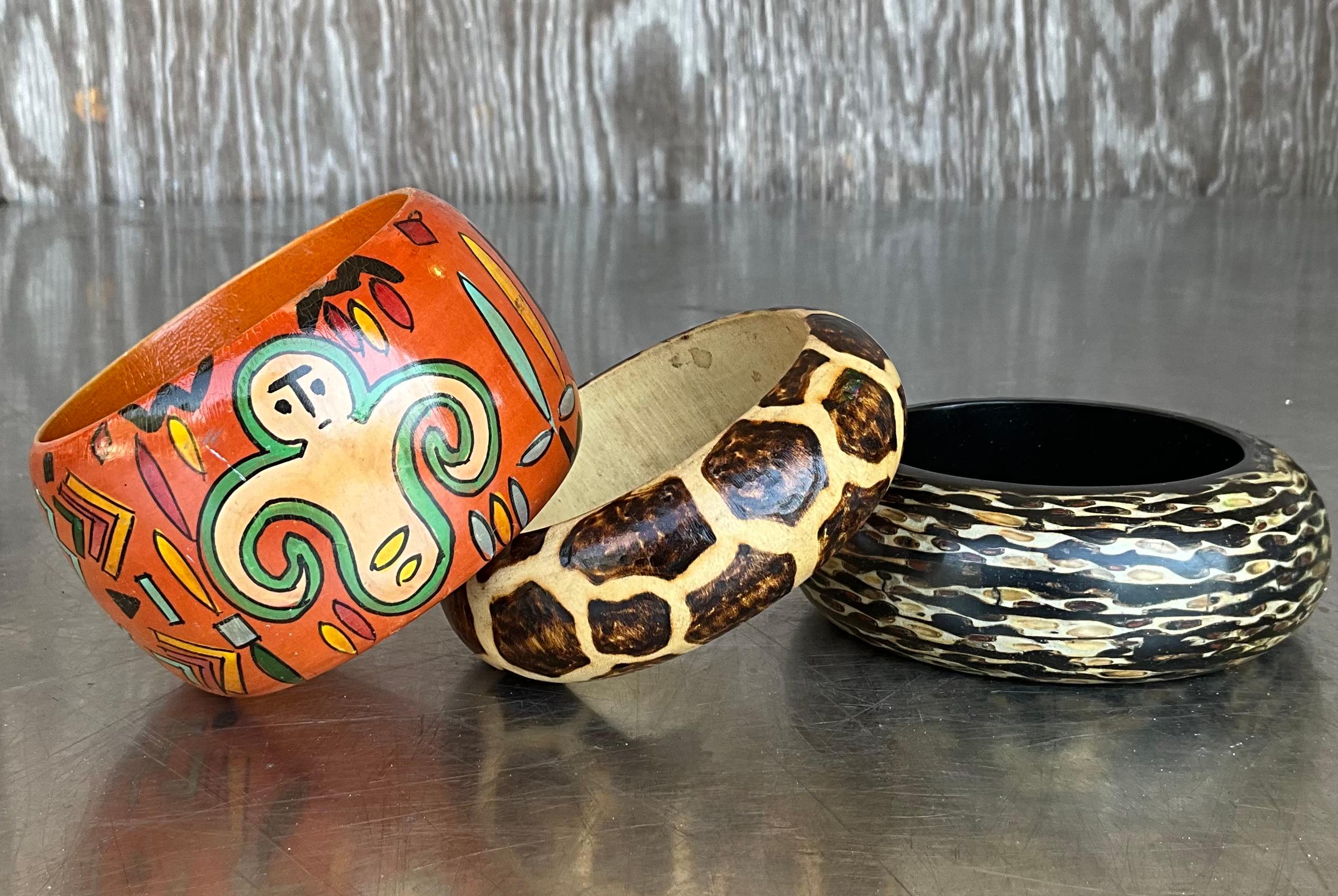 Questo set di 3 bracciali vintage in legno di ispirazione africana è un suggestivo tributo alla ricchezza artistica e culturale del continente africano. Scolpito a mano in legno naturale, ogni braccialetto presenta dettagli unici - che vanno da