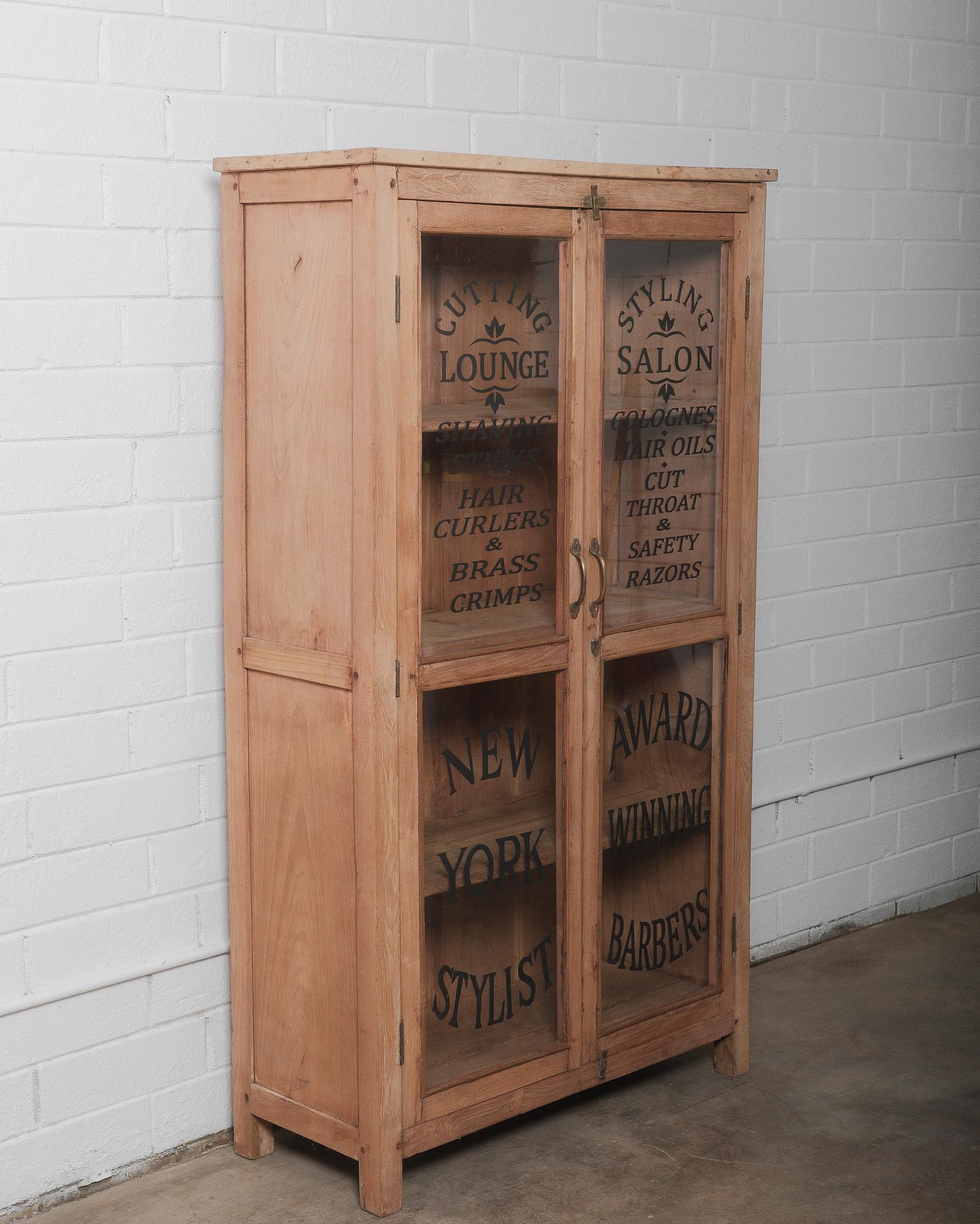 Cette vitrine ancienne en bois est une pièce remarquable du début du 20e siècle, avec des panneaux de verre peints à la main sur ses doubles portes. Le lettrage peint suggère qu'il était à l'origine utilisé pour la vente au détail ou la présentation