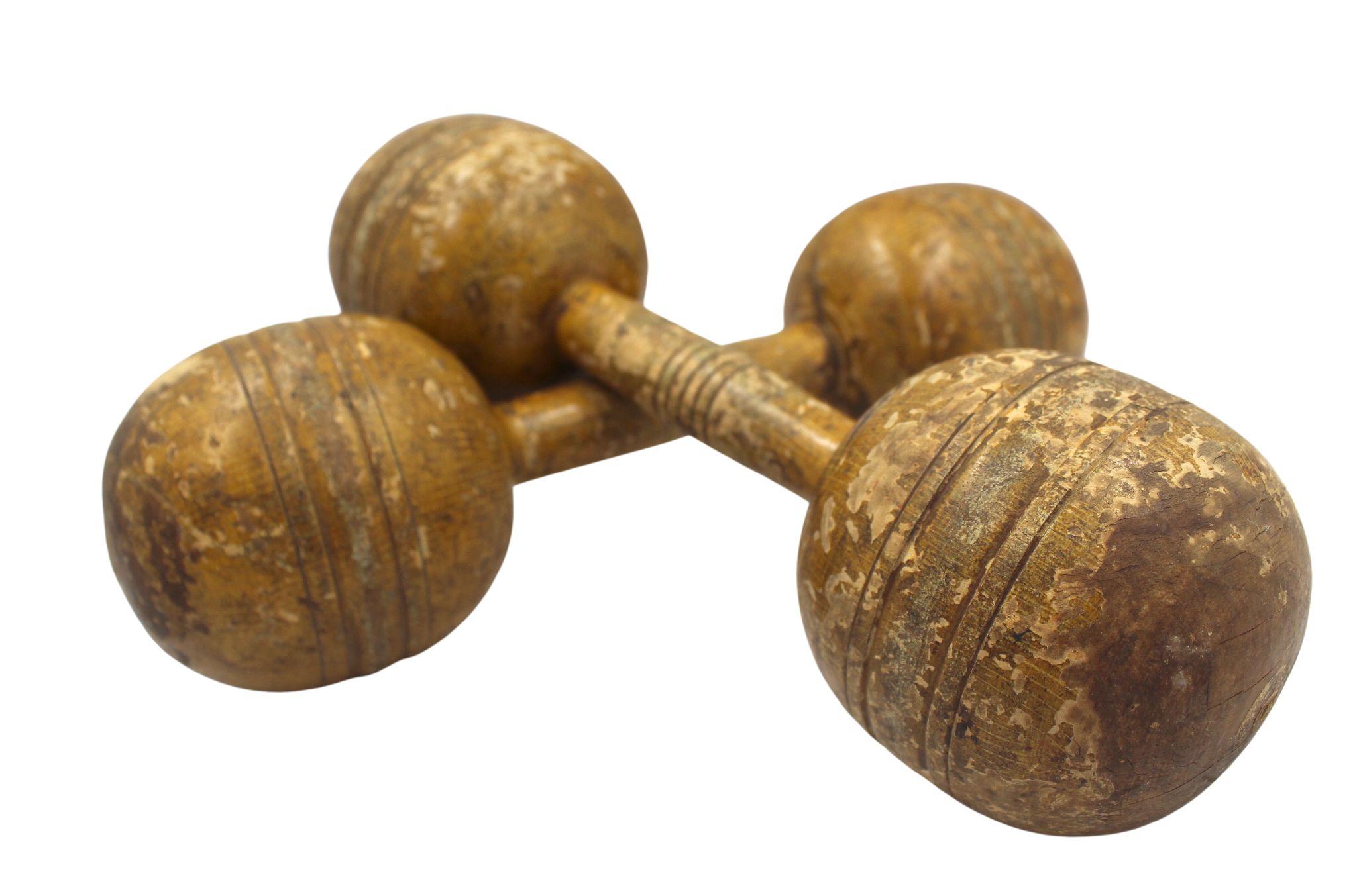 Presented is a set of vintage wooden dumbbells. The dumbbells are fixed-weight and constructed of hand-turned solid wood. They have incised lines at center for grip and around the balls for ornamentation and to keep the dumbbells from rolling. A