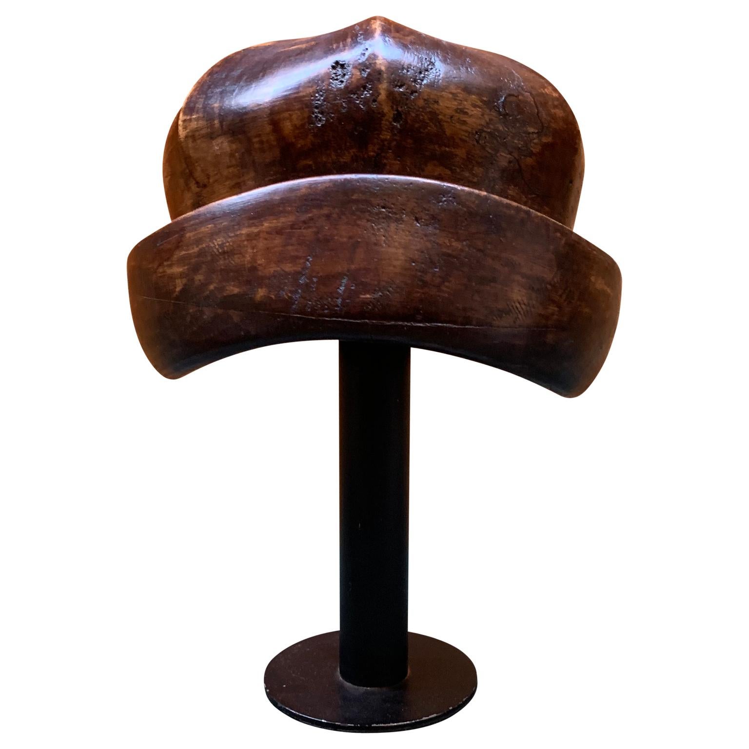 Vintage Wooden Hat Mold
The hat mold is displayed on a black metal stand.