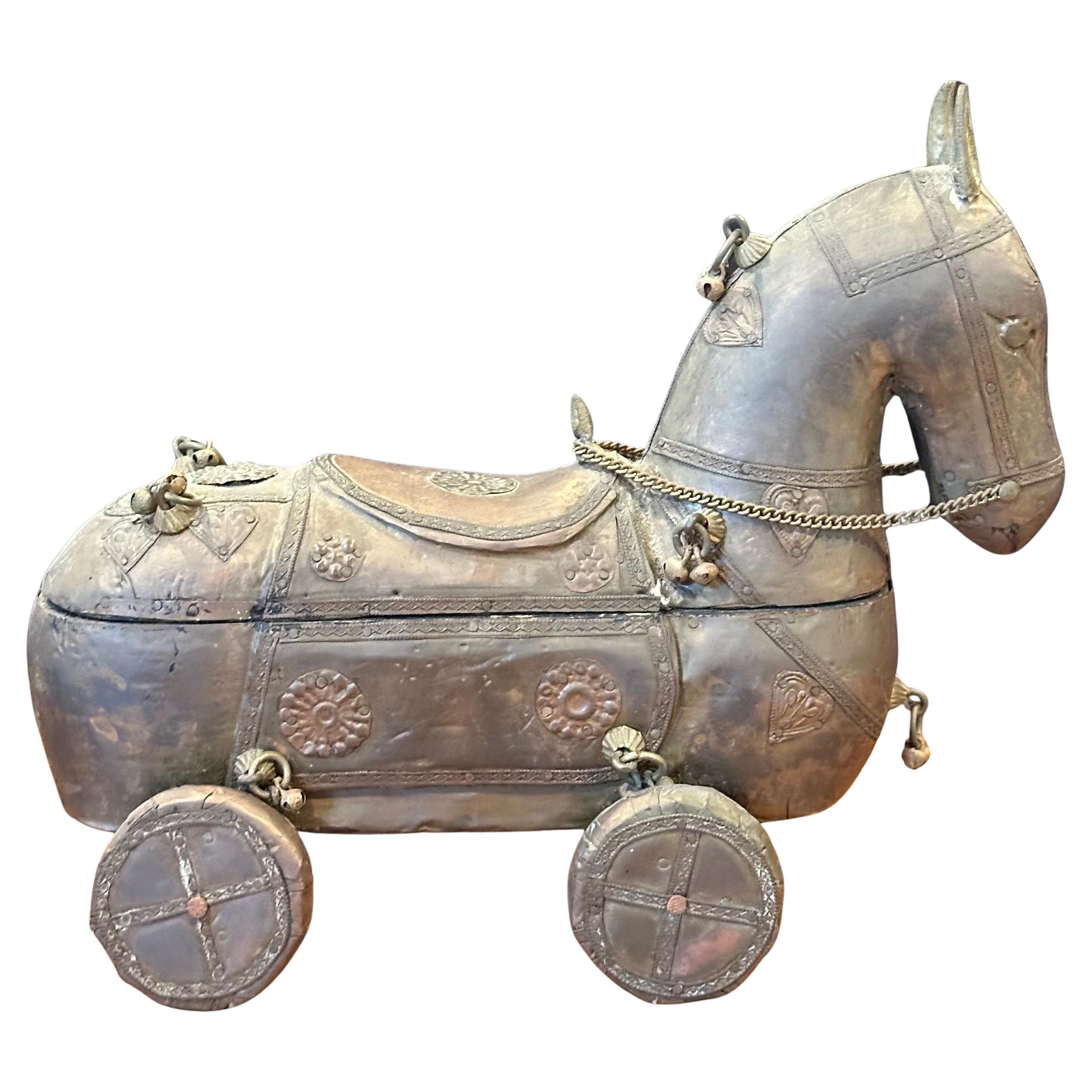 Caballo de juguete indio vintage de madera con ruedas, hacia la década de 1970. La pieza tiene un pestillo en la parte delantera que te permite girar la parte superior para abrirla y acceder a un compartimento de almacenamiento oculto. El caballo es