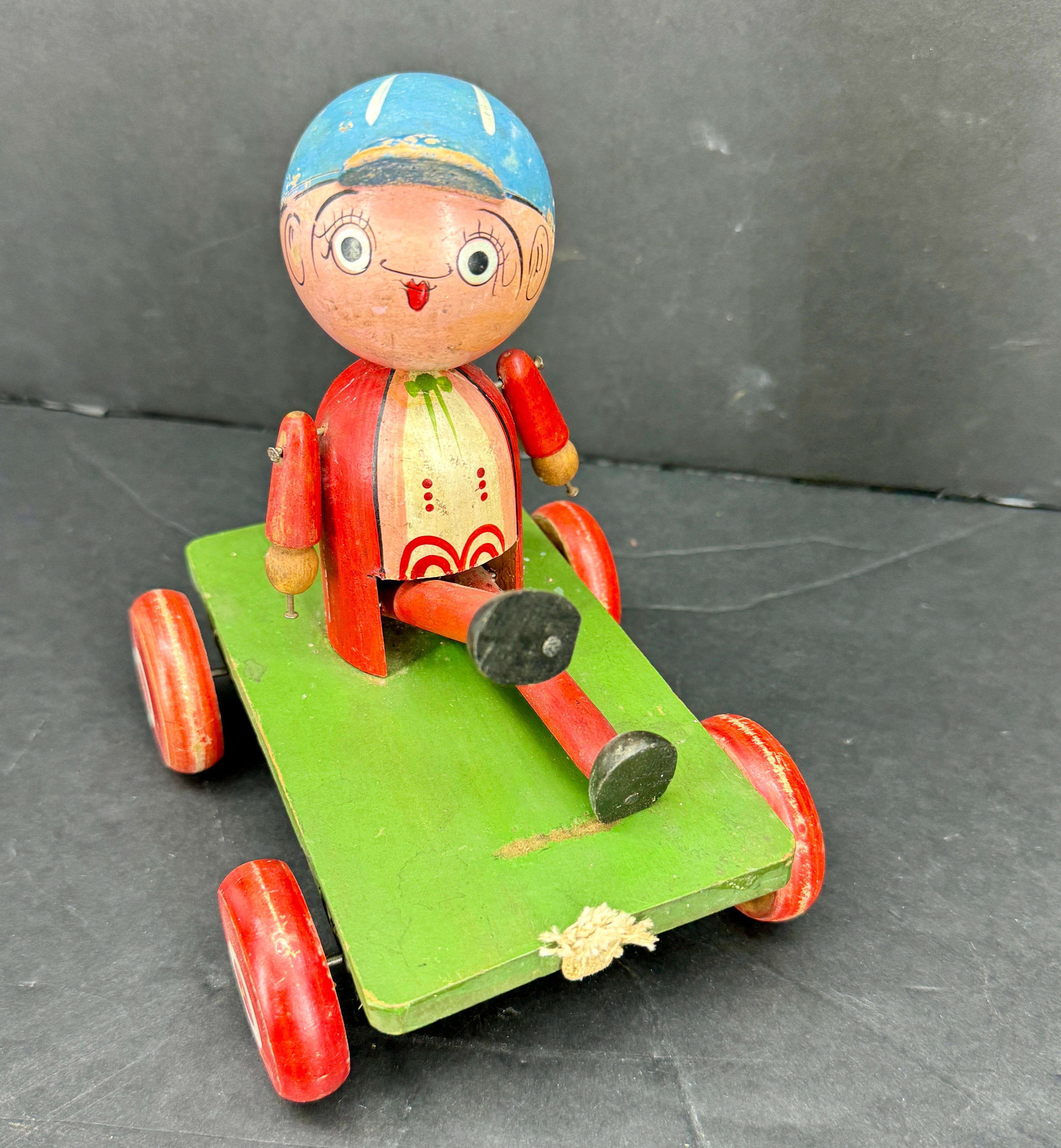 Classic Jaymar Wooden Pull Along Toy from the 1930's. The toy features a boy sitting atop four wheels. This vintage child's toy is a wonderful piece to add to a current collection or start a new one. 