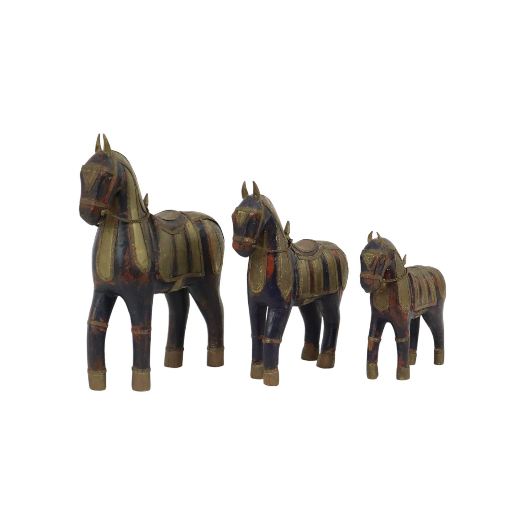 Ensemble de 3 chevaux Marwari en bois recouverts de cuivre, ensemble de statues de caractère, Inde, vers le milieu du 20e siècle.

Statues de taille croissante, teintées en bleu foncé profond, oreilles et queue en laiton, décorées de ferrures en