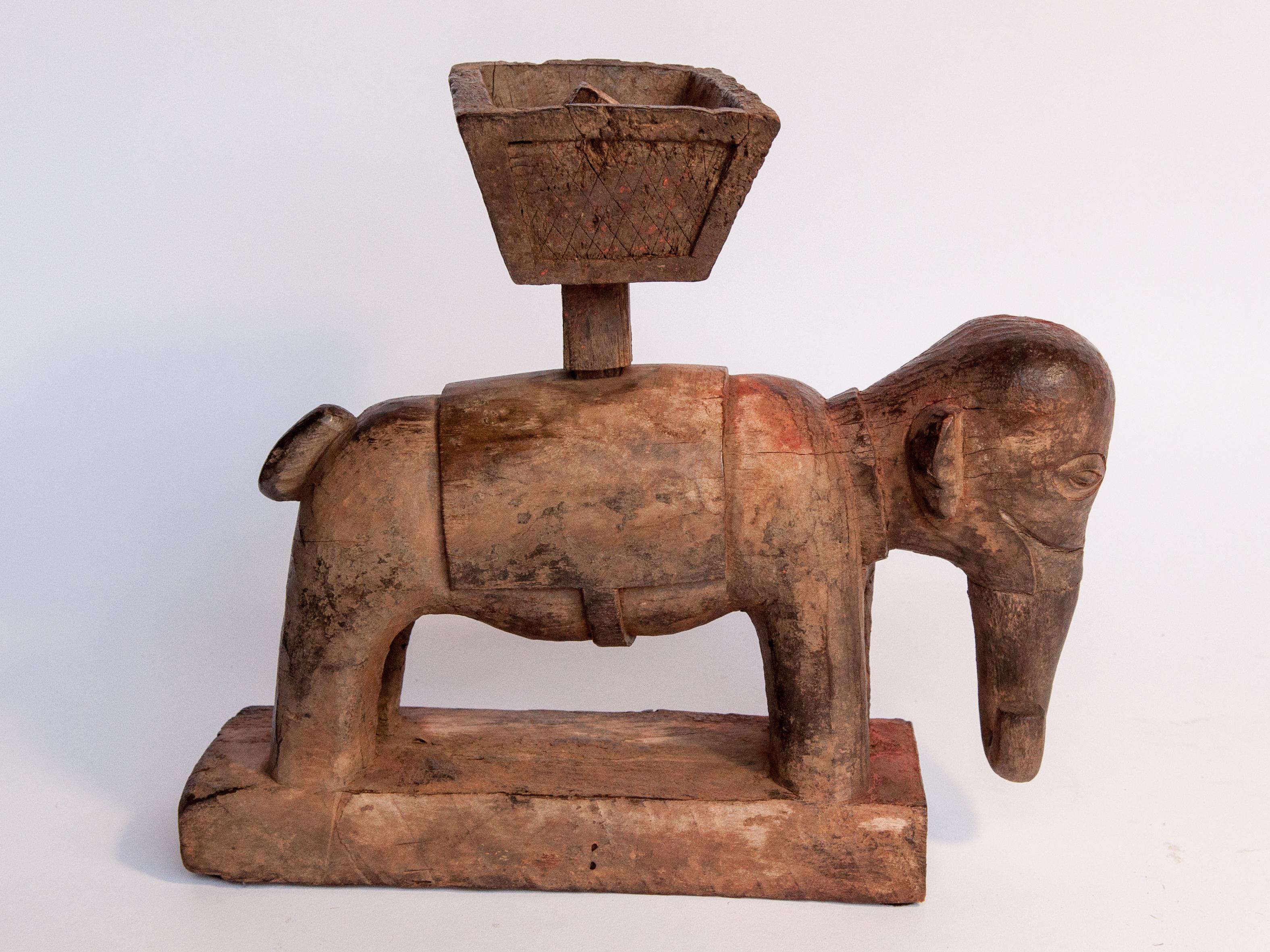 Vintage wooden offering holder elephant motif Newar of Nepal. Mid 20th Century.
This carved wooden elephant was placed in front of a household shrine to hold offerings of rice, flowers or other small objects, made to the Deity. Such holders are