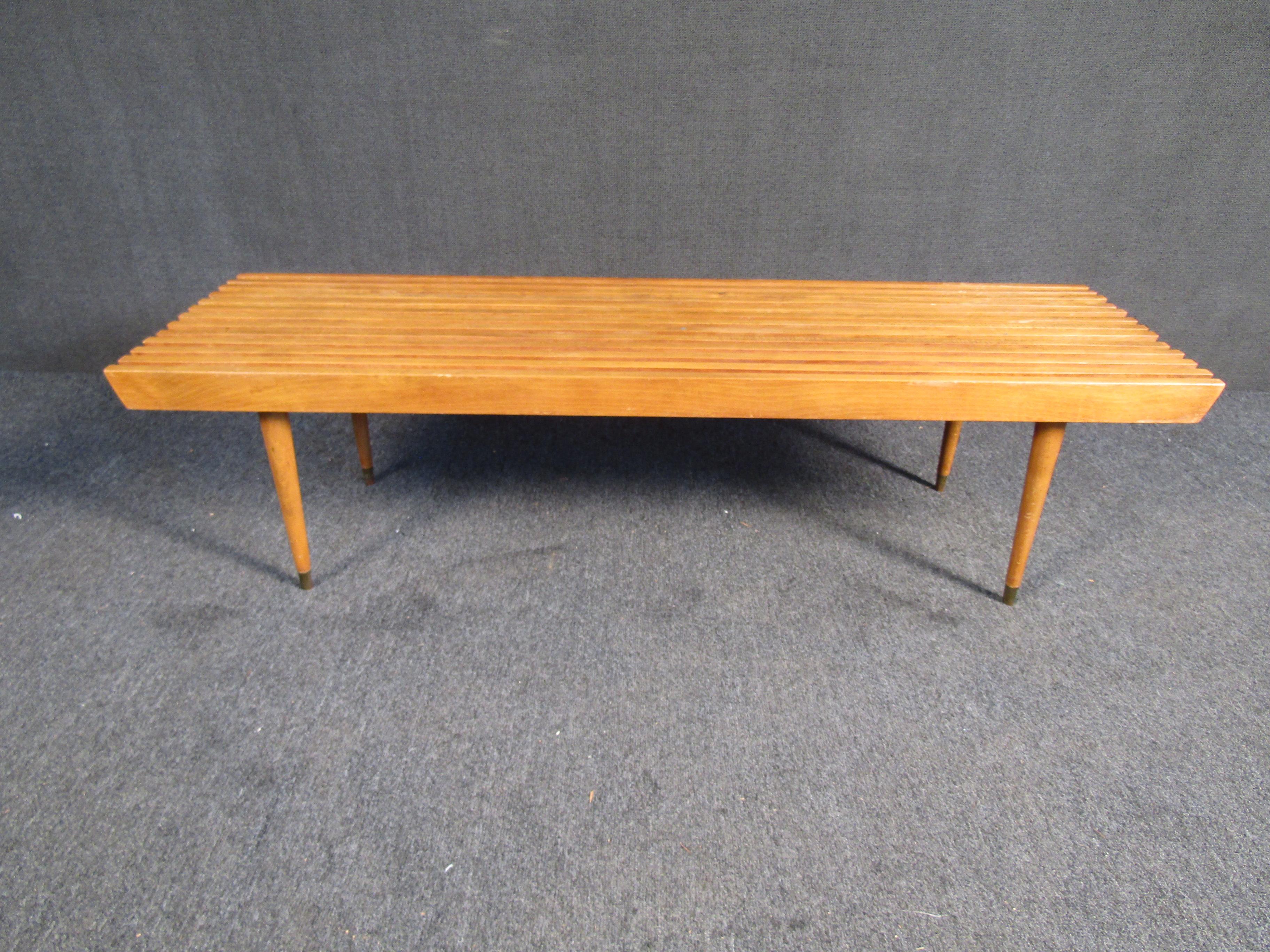 This hardwood slat bench features with tapered legs. Standing at a height of 16 inches, this vintage modern slat bench makes the perfect piece for occasional seating or even as a tall coffee table. 

Please confirm item location (NY or NJ).
