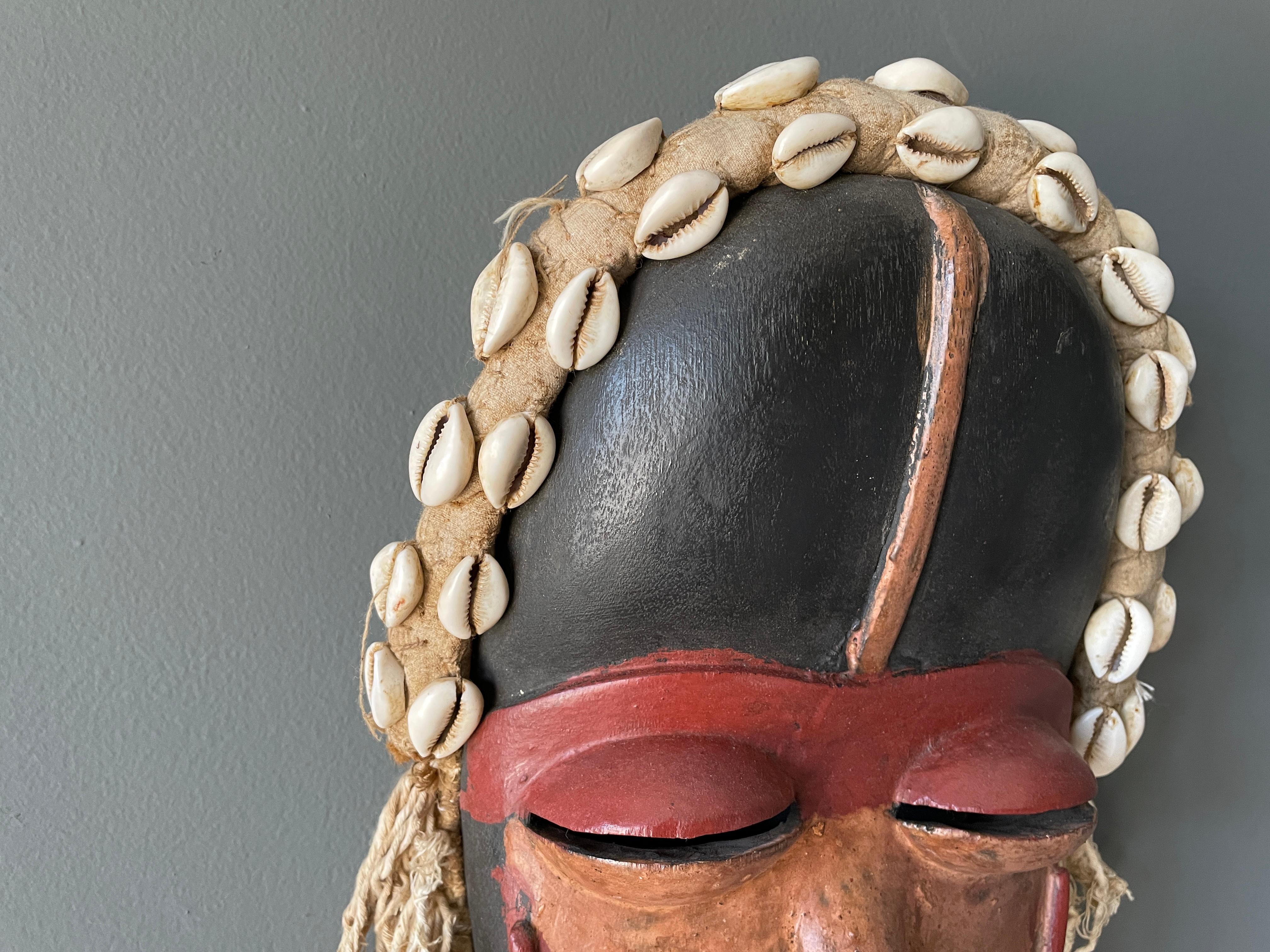 Vintage hand carved Biombo tribal mask. Deep, vibrant colors with sea shell accents. A wonderful accent piece for any room.
