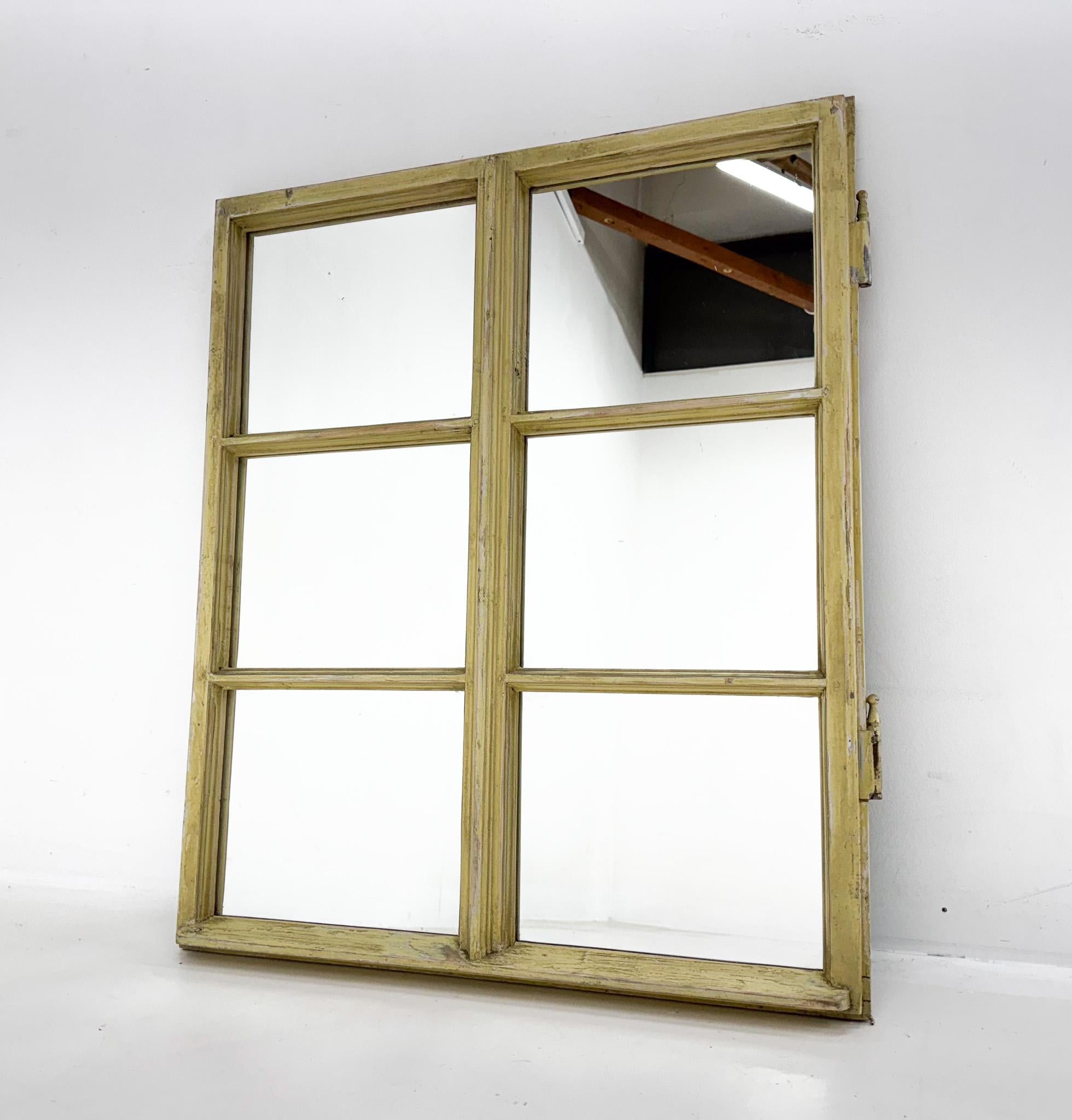 Vintage wooden window converted to a mirror with its original patina and preserved metal details. 