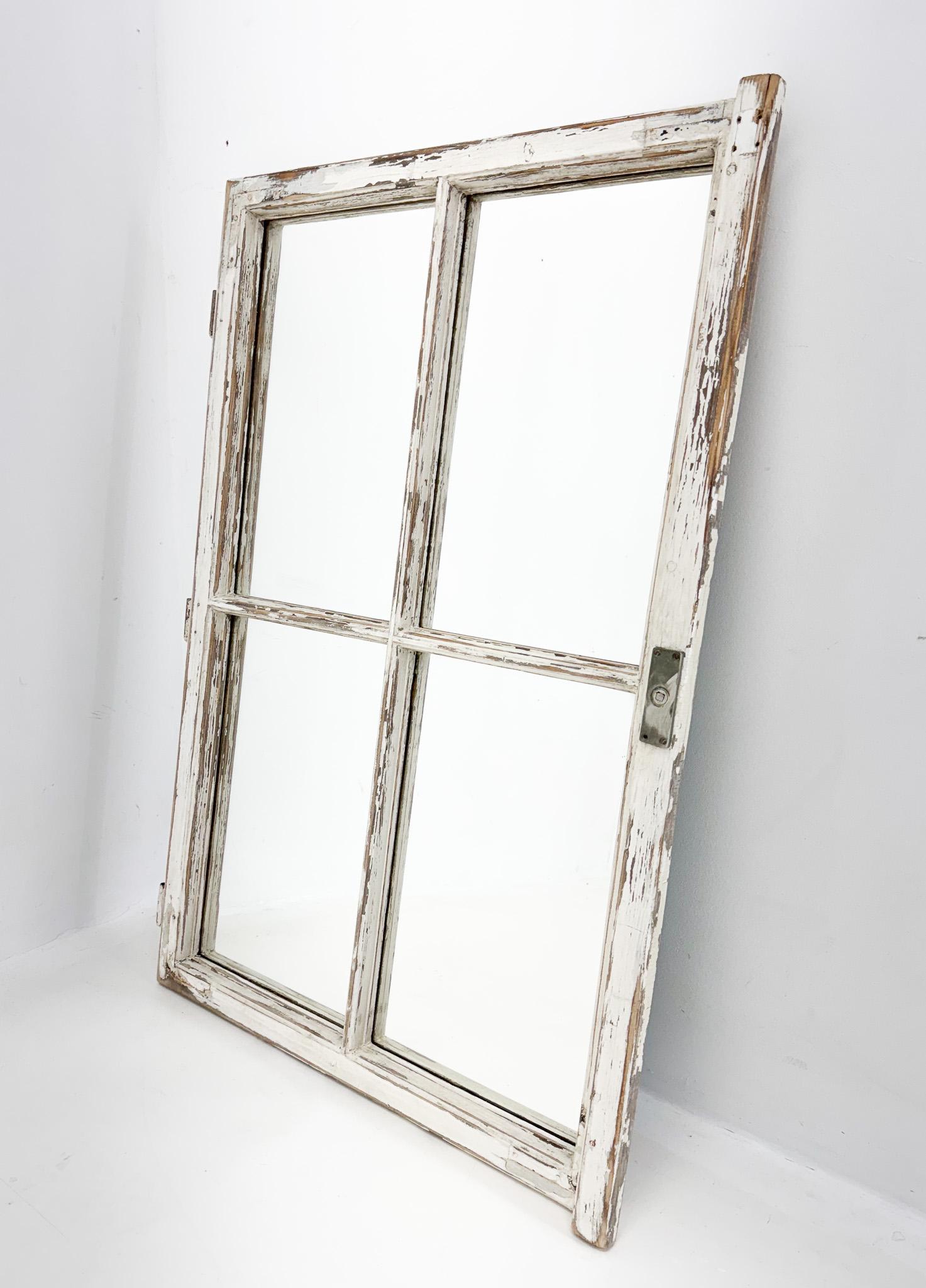Vintage wooden window converted to a mirror with its original patina and preserved metal details. 