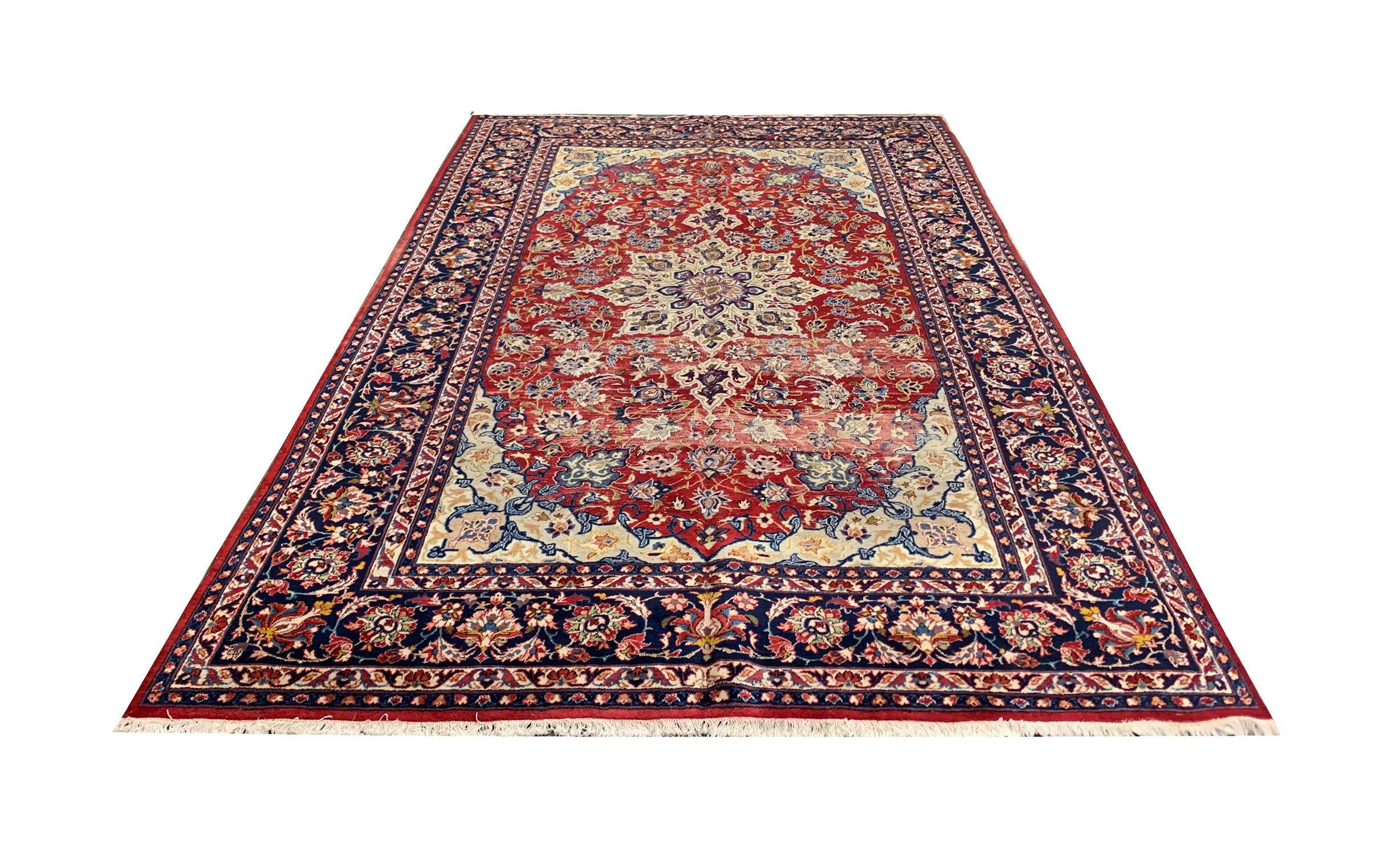 This traditional vintage carpet is a fine example of carpets from the 1940s. Woven with a rich red background with blue, beige and cream accents that make up the floral symmetrical design. This has then been framed with a bold repeating pattern