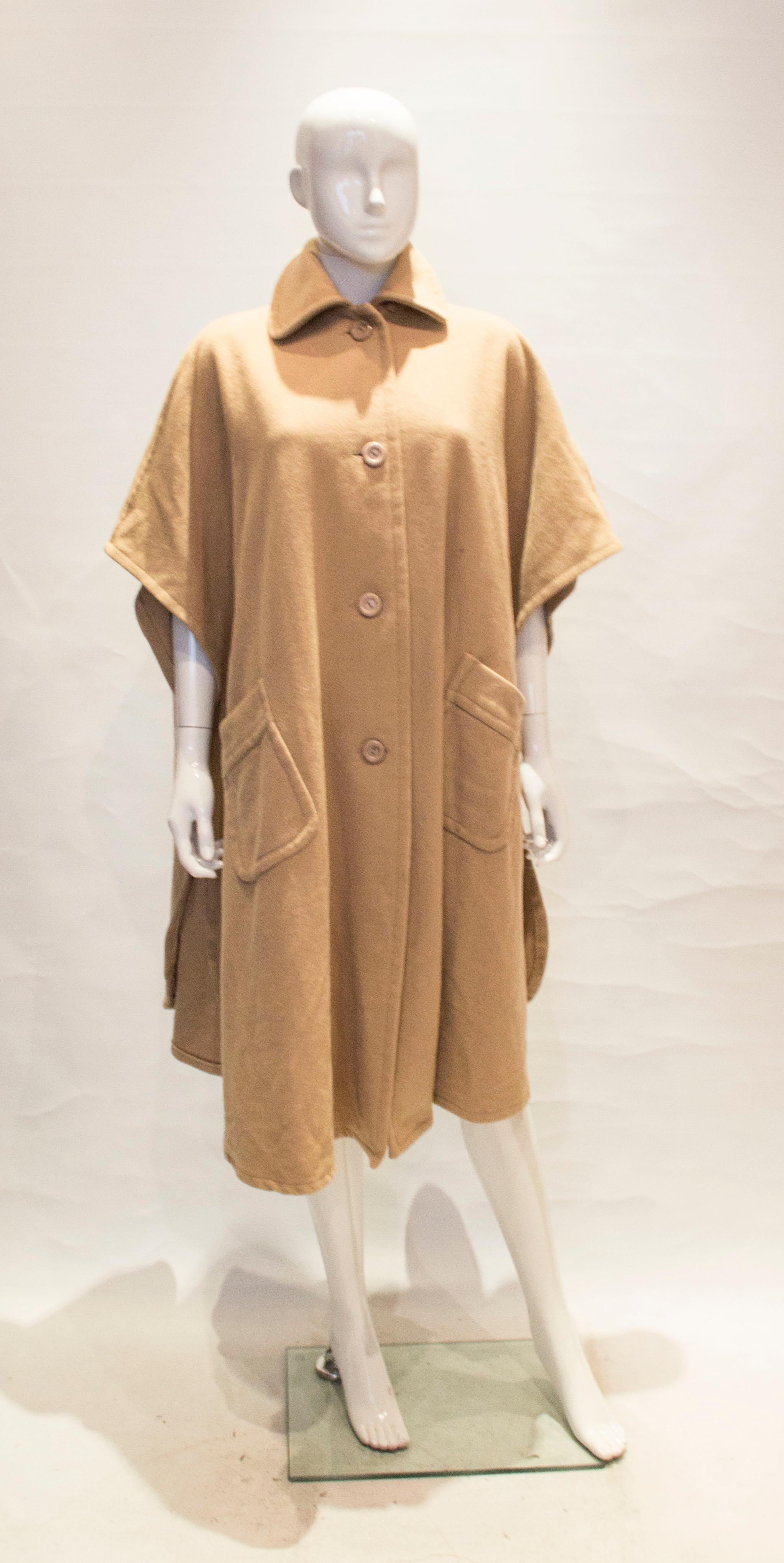 A great cape for Fall. In caramel colour wool, the cape has a button front opening, collar and two front pockets.  Bust up to 48'' length 43''