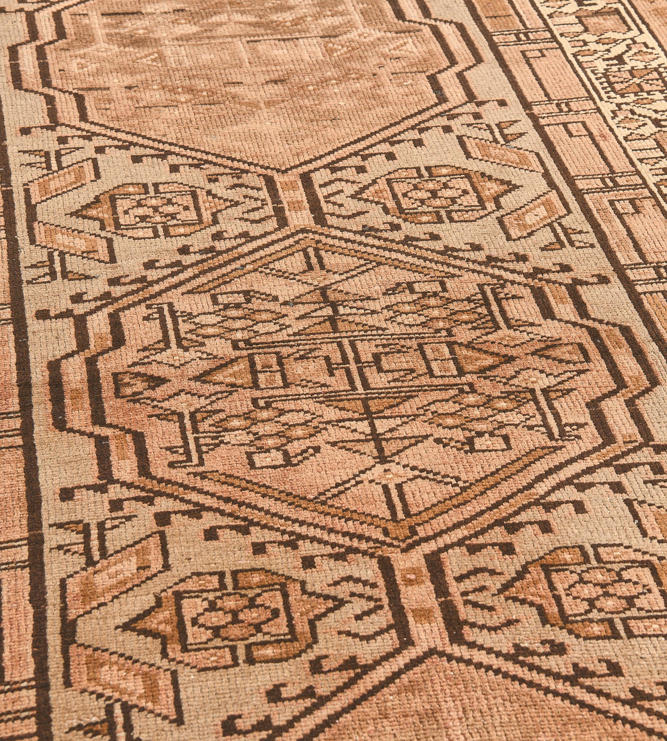 This antique, circa 1940, Heriz runner has a buff-brown field with a central column of linked light terracotta-brown hooked lozenges each containing a central panel containing angular floral and lozenge vine, flanked by lozenges and stylised floral