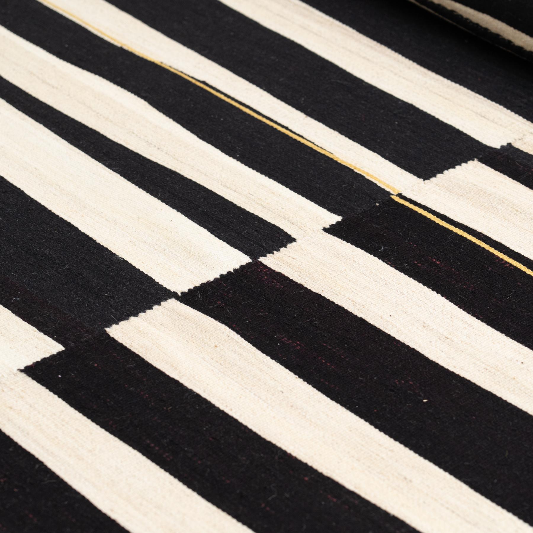 This striking vintage Kilim rug, handwoven around the 1970s, features a bold and timeless design in classic white and black tones. With its modern geometric patterns, this rug is an embodiment of minimalist sophistication, offering a dynamic