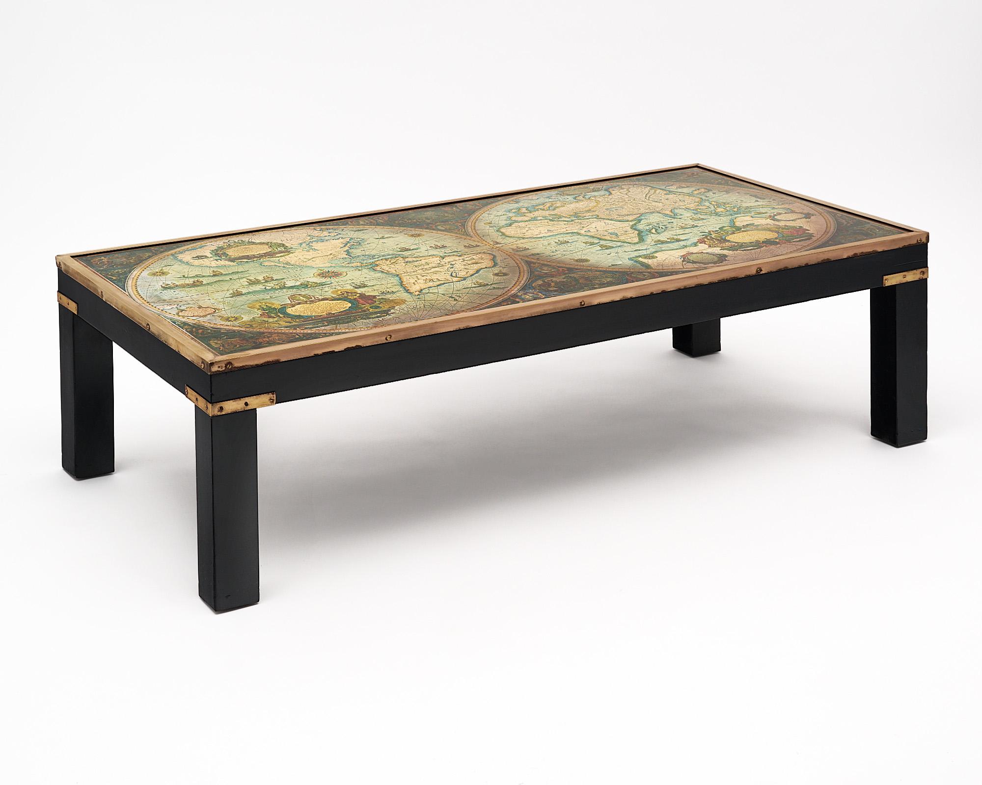 Coffee table from France made of ebonized wood featuring gilt brass trims with a clear glass top over a vintage map of the world. The map also includes portraits of royalties. The map is reproduced from a color copper plate of the 17th century map