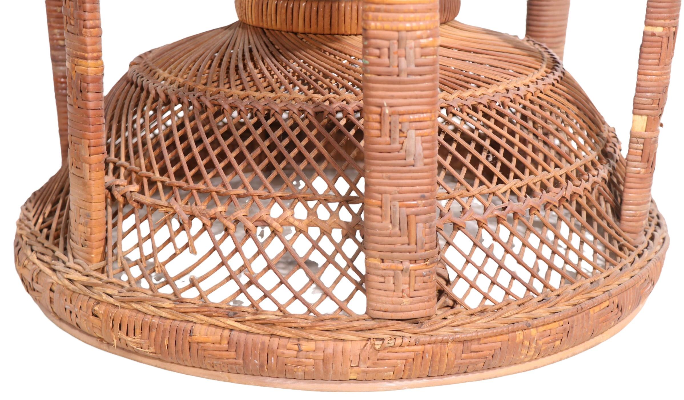 Iconic wicker Emmanuelle, or Peacock chair in very good, original condition. This dramatic example features a large back, intricately woven armrests on a twist waisted form base, it still retains the period and original Made in Hong Kong paper
