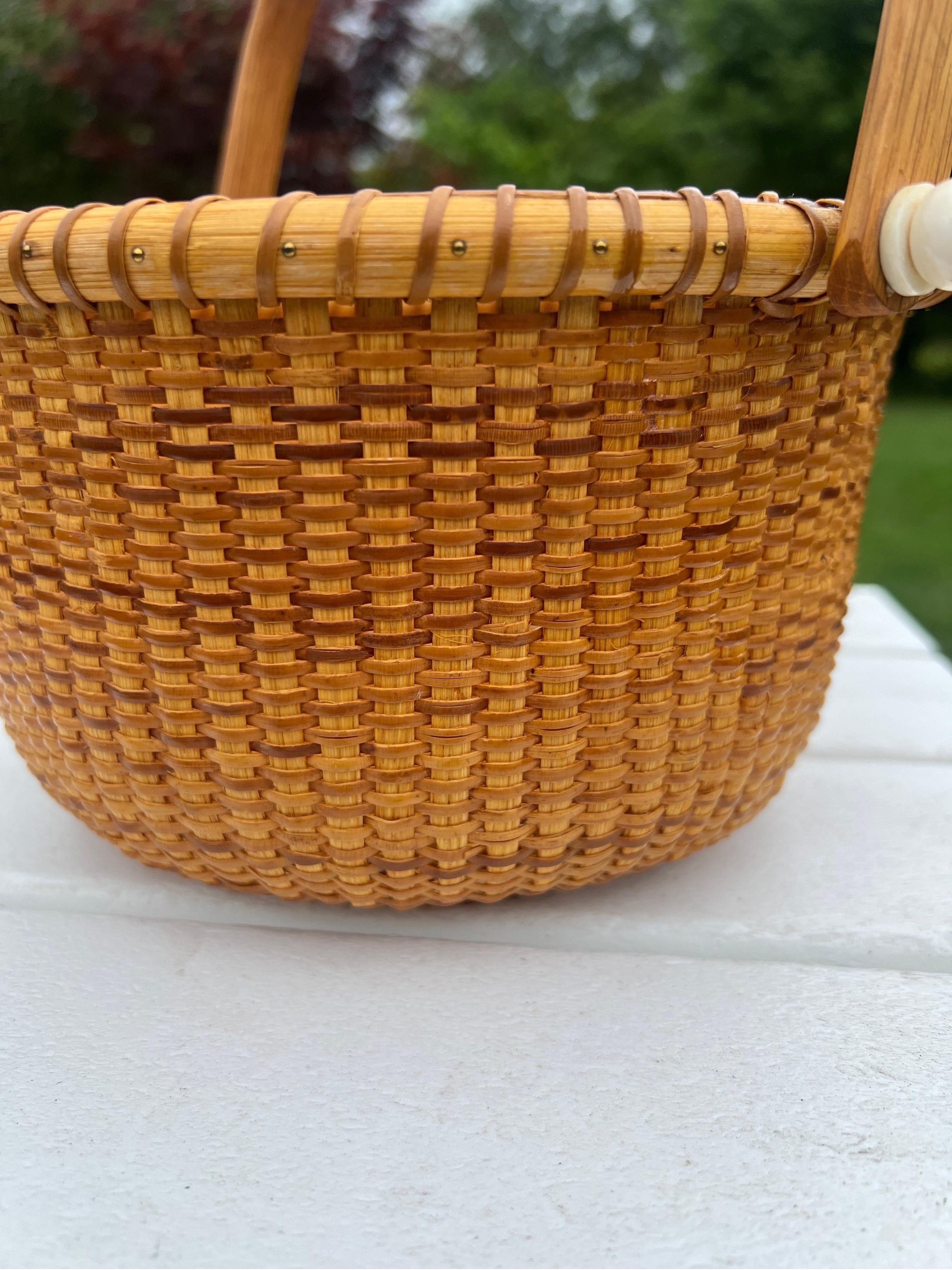 This vintage Nantucket basket is hand made with native wood base, woven wicker body, pin accented rim and the handle is connected with traditional nantucket animal bone. Unmarked.
