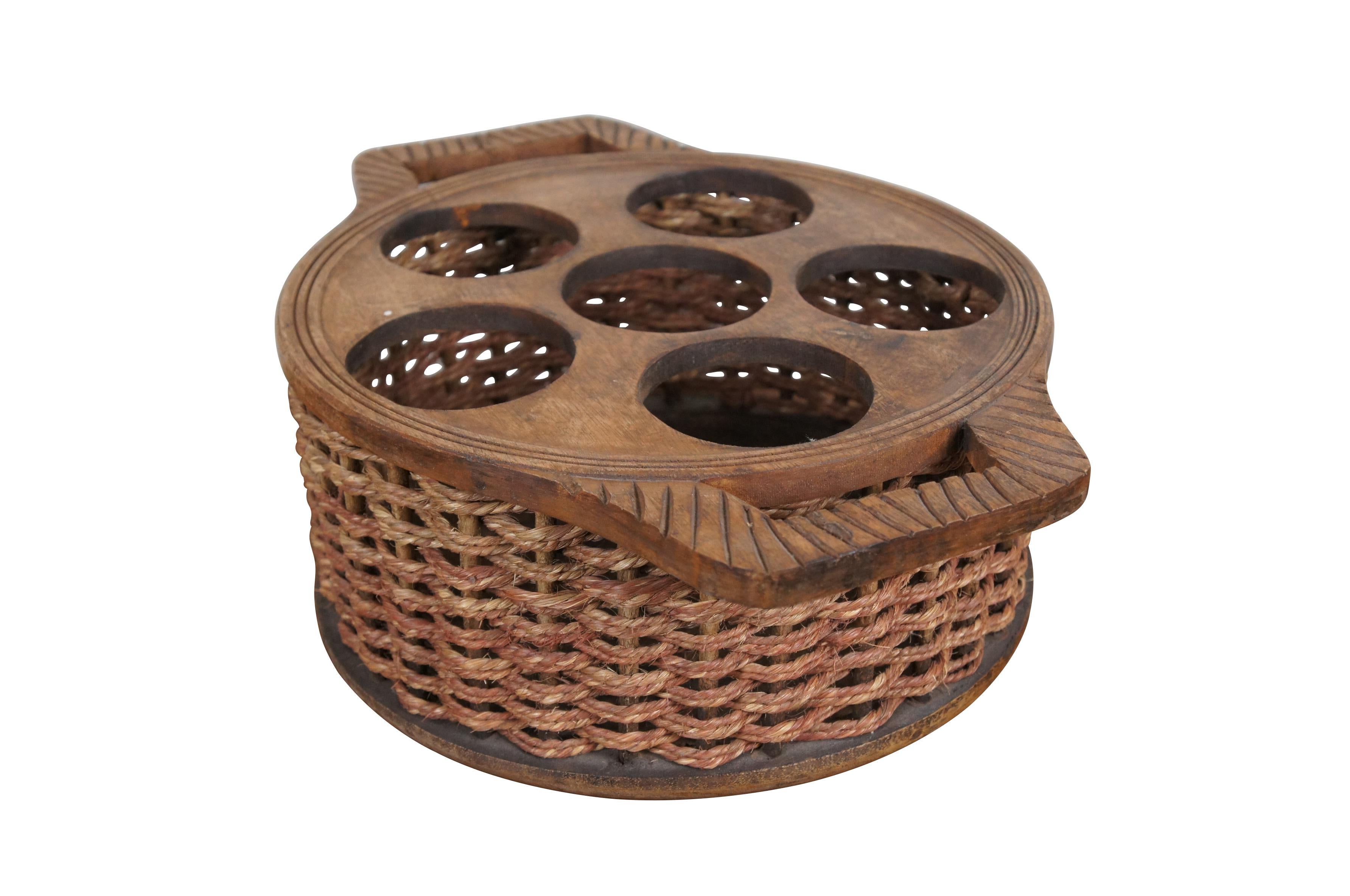 Cesta para servir/transportar/almacenar vino de granja de finales del siglo XX. Base y parte superior redondas de madera con asas talladas y huecos para 6 botellas de vino; laterales tejidos con cuerda. Fabricado en la India.

Dimensiones:
19
