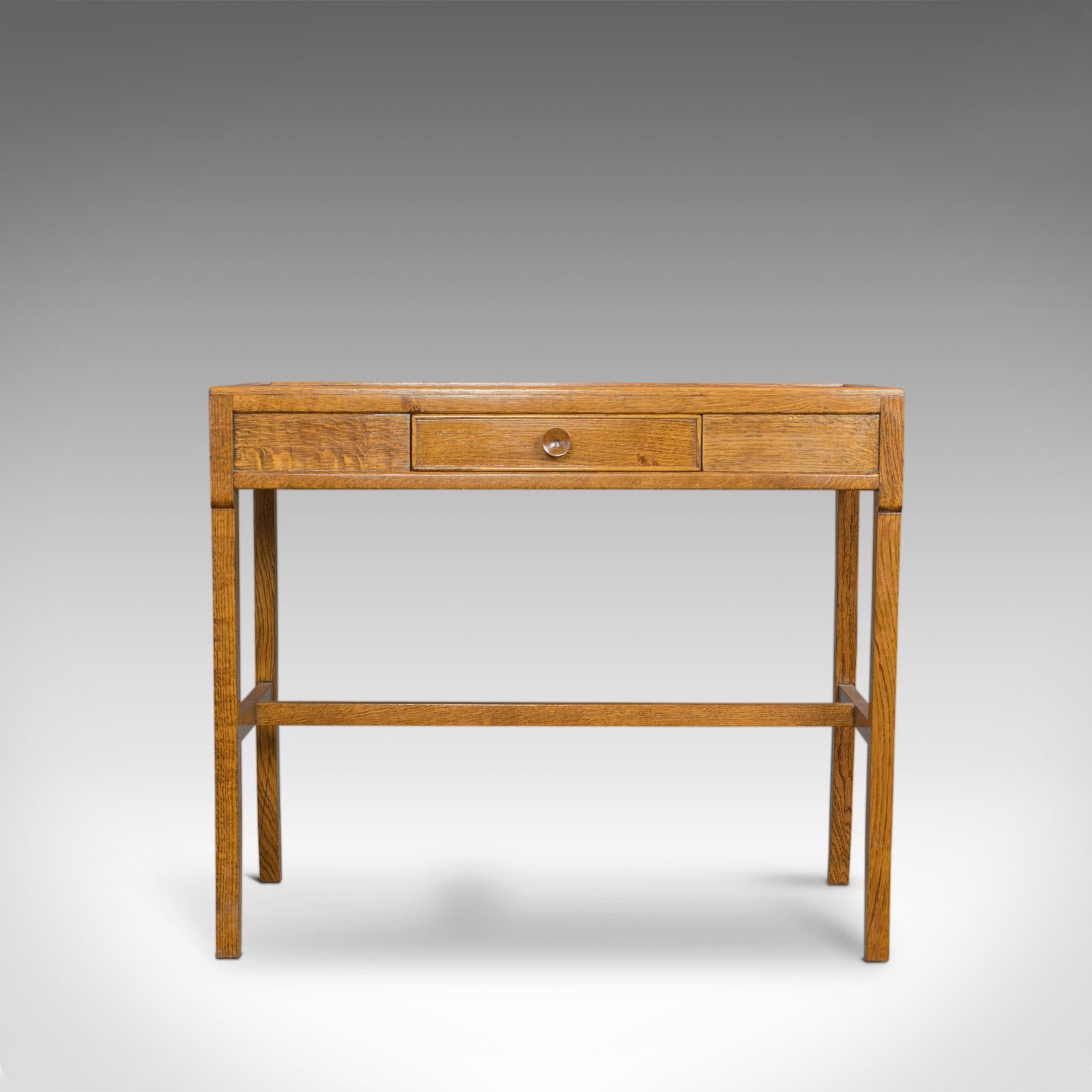 This is a vintage writing desk or side table. An English hall console table dating to the 20th century with Arts and Crafts overtones.

Select oak displays Fine grain interest and a desirable aged patina
Light caramel hues in a wax polished