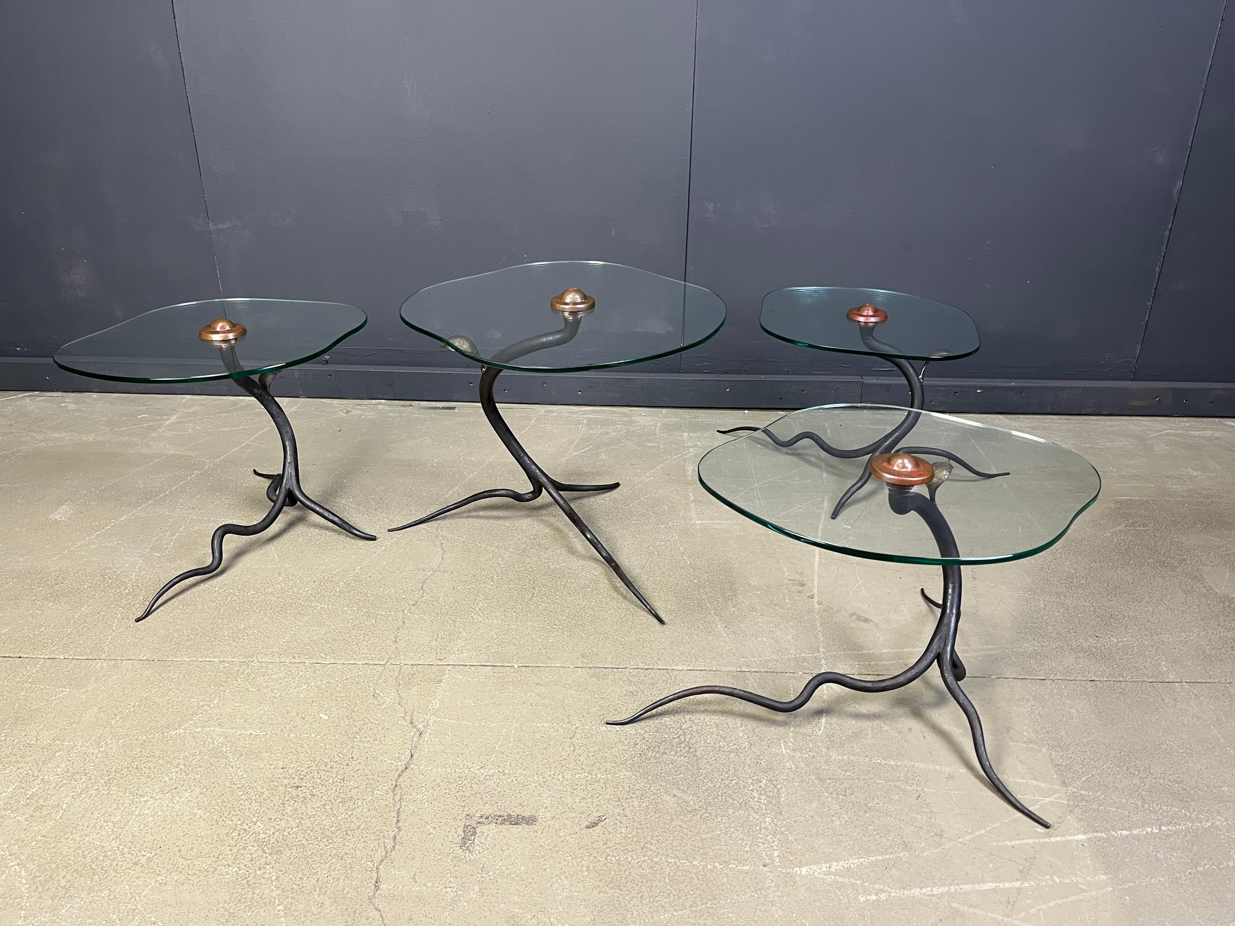 Exclusive vintage nest of coffe or side tables.

The organic tree shaped bases are made of bent wrought iron with brass leafs supporting organically shpaed clear glass tops fixed onto the base thanks to a copper coloured cap.

Beautiful as a set,