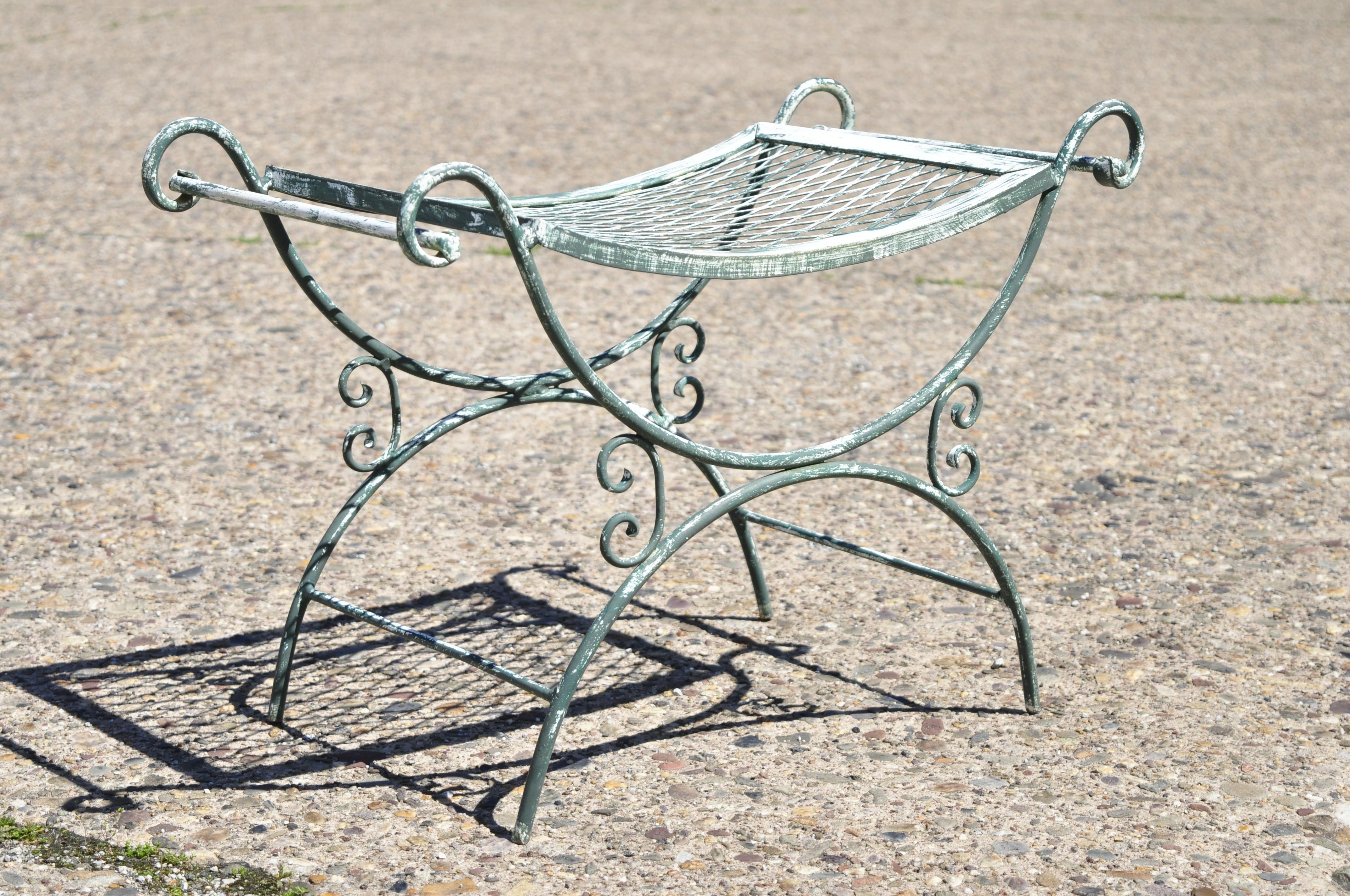 Vintage wrought iron curule mesh bench mid century green white Hollywood Regency. Item features curved mesh seat, X-form curule base, twin handles, wrought iron construction, painted distressed finish, very nice vintage item, quality American