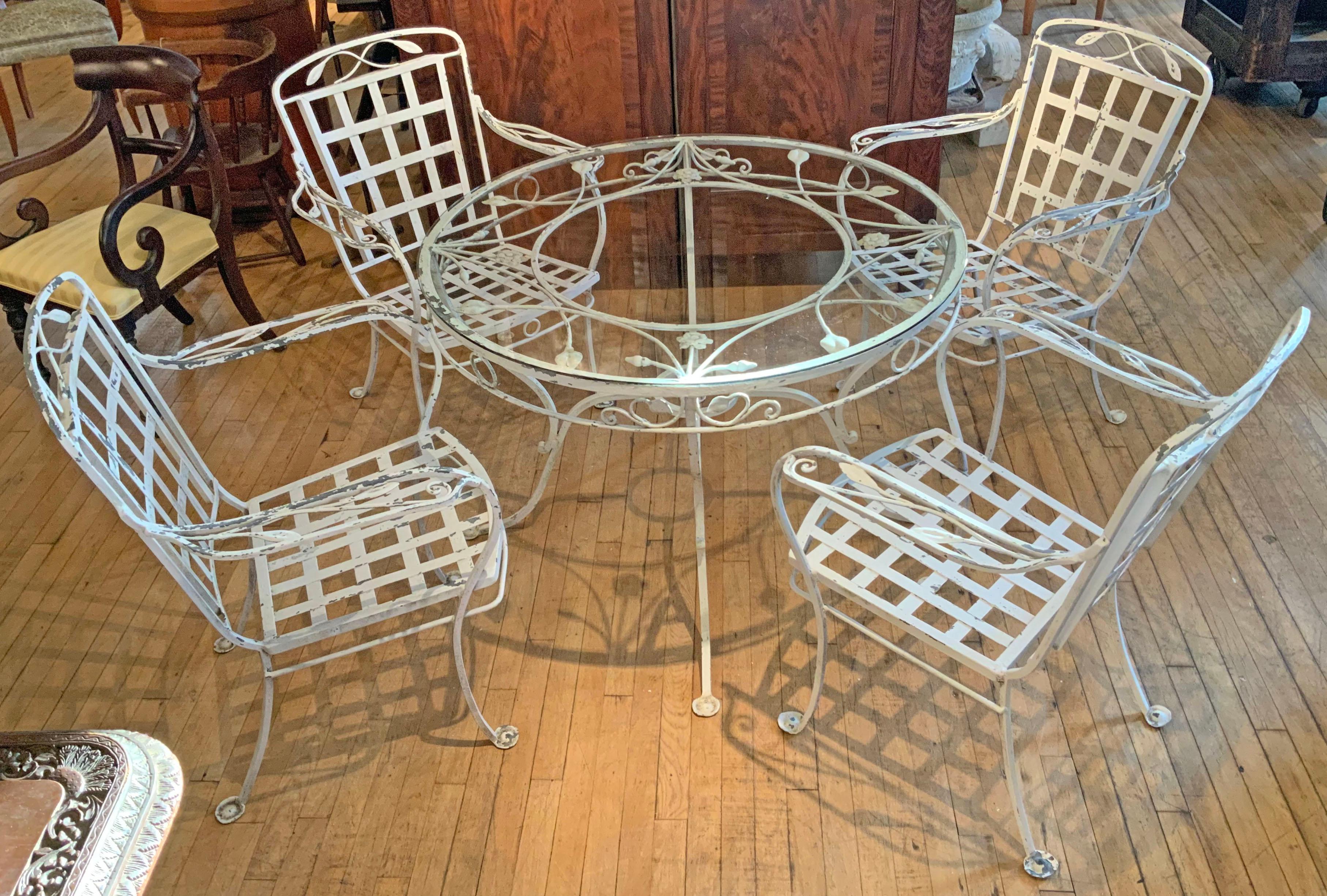 A beautiful 1950's wrought iron dining set by Salterini. Beautifully made with heavy wrought iron and wonderful details. The set contains a round glass top table, and four armchairs. 

Original white finish, which is flaking in many areas. we can