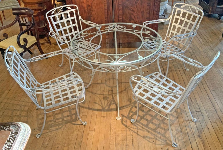 A beautiful 1950's wrought iron dining set by Salterini. Beautifully made with heavy wrought iron and wonderful details. The set contains a round glass top table, and four armchairs. 

Original white finish, which is flaking in many areas. we can