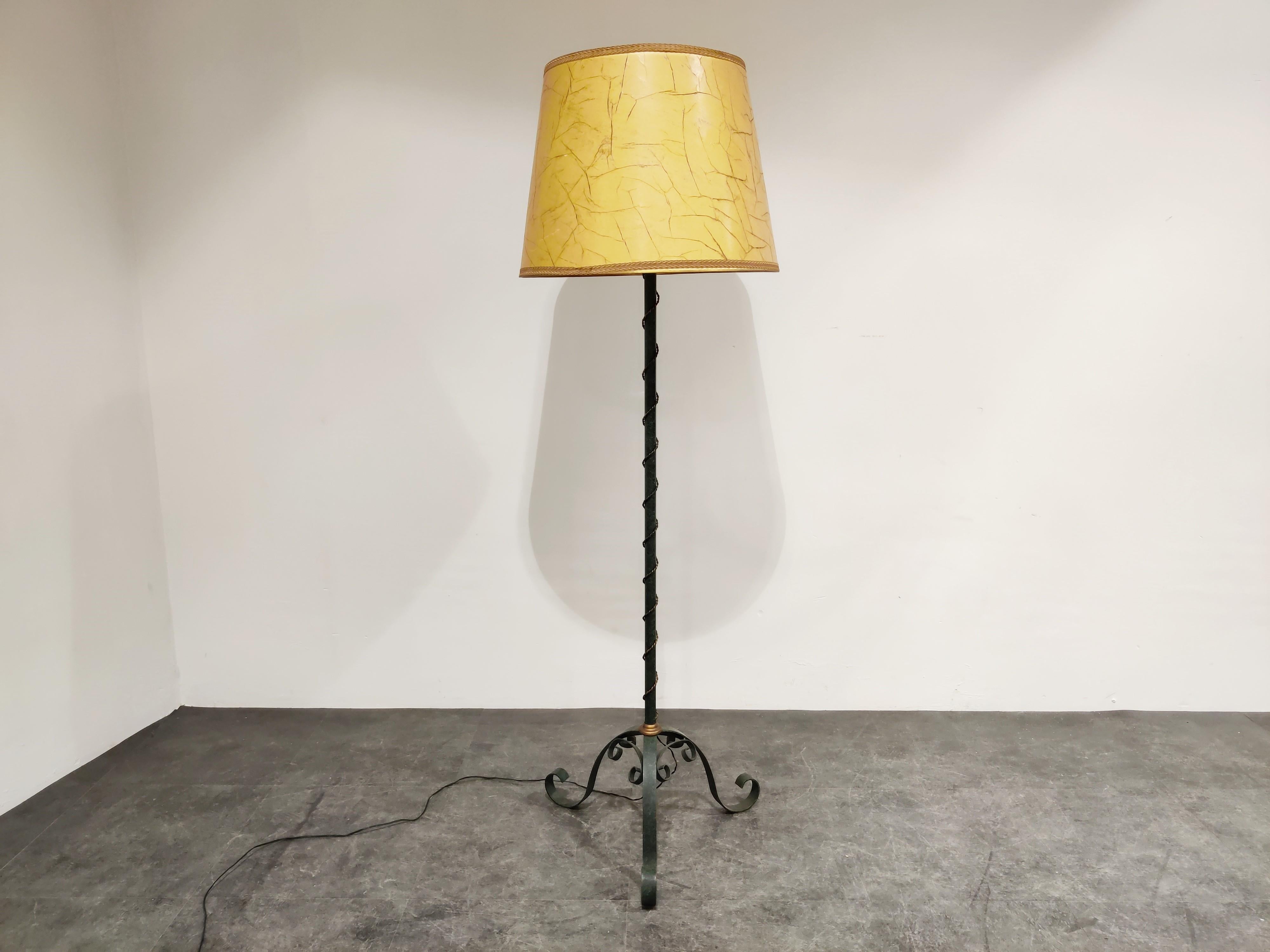 Elegant midcentury wrought iron floor lamp.

Beautiful tripod scroll legs.

The floor lamp has it's original parchment lamp shade.

The lamp dates from the 1950s - 1960s and was probably manufactured in France. 

It emits a warm and