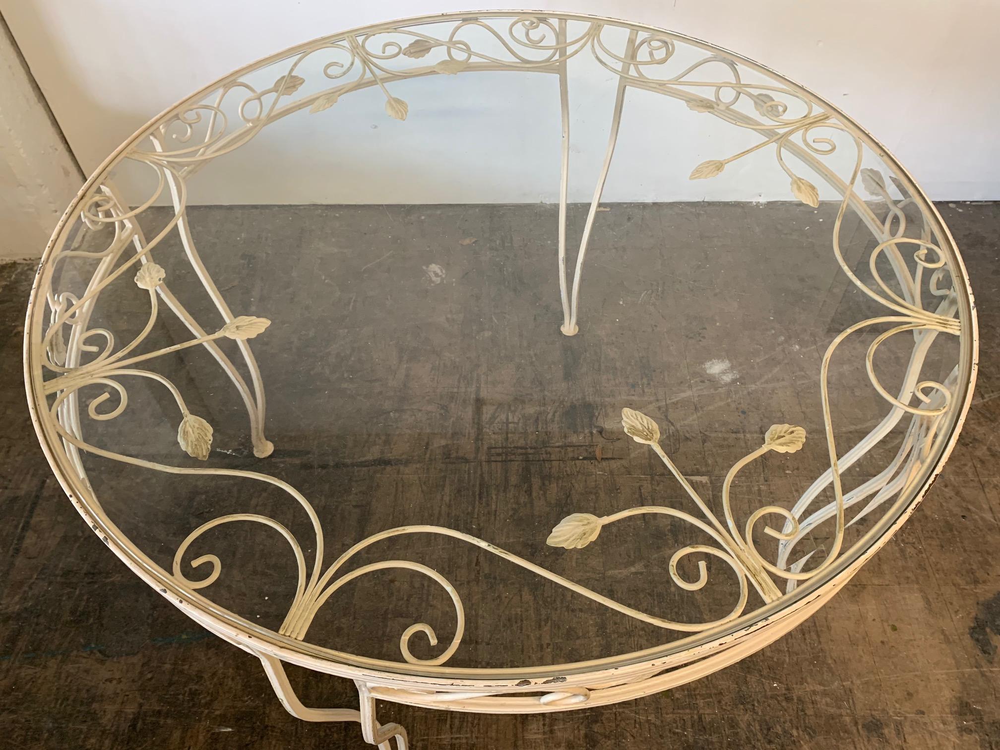 Vintage wrought iron patio table features leaf motif detailing and glass top. Good vintage condition with some paint loss to original finish.
Measures: 42.5