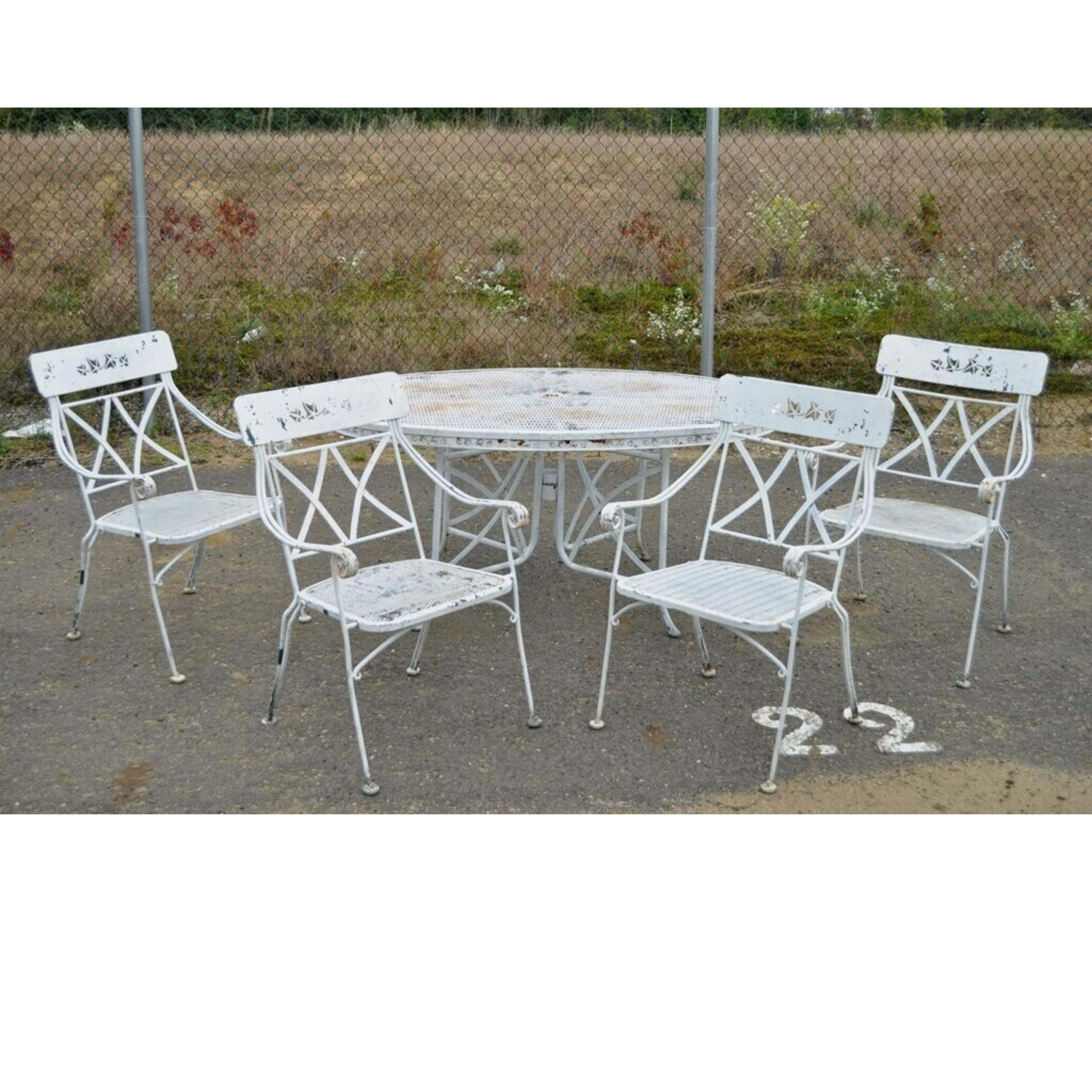 Vintage Wrought Iron Salterini Style Garden Patio Dining Set - 5 Pc Set. Item features 4 curule armchairs with cut-out leaf pattern and oval table with umbrella hole. Circa Mid 20th Century.
Measurements: 
Table: 28