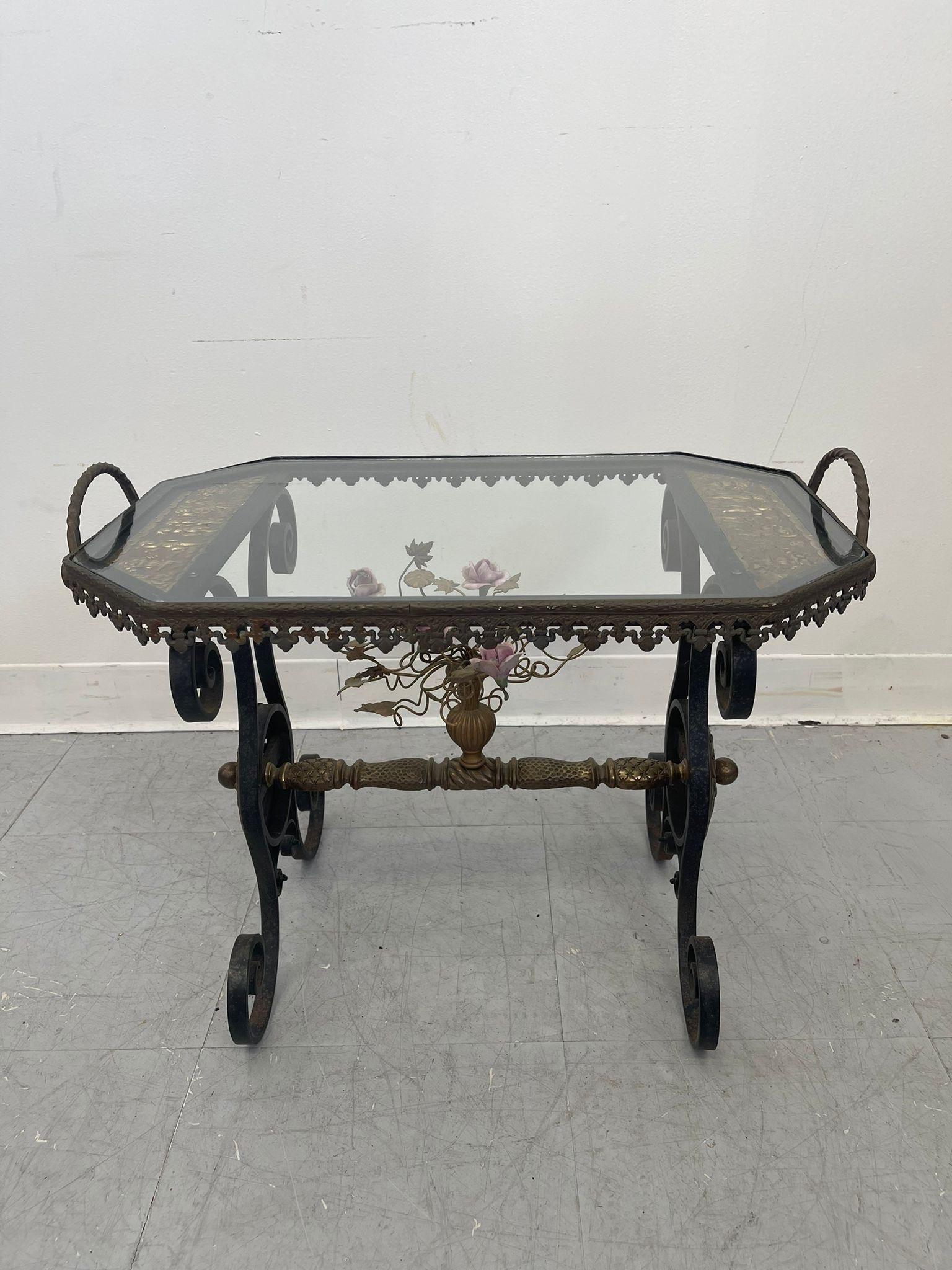 This elegant and unique Side Table features a removable glass tray with twisted iron handles. The base is a work of Art with spiral curved legs and central stretcher from which a gift metal urn with an bouquet of iron flowers rests. The top has two