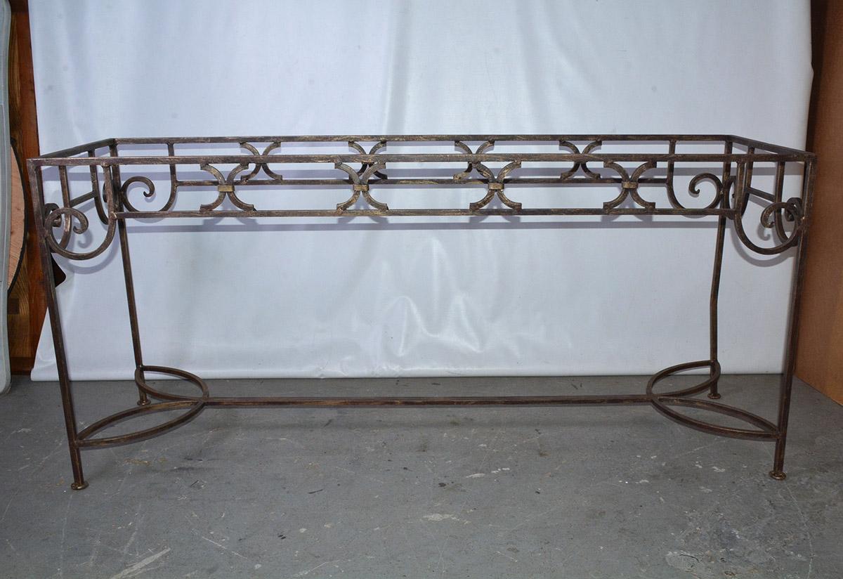 The vintage wrought iron console table or sofa table has a brushed gilt finish and is handcrafted with elegant scroll-work and other detailing. The feet have flat iron pads. With a glass, stone or marble top, can you picture it in a hallway, dining
