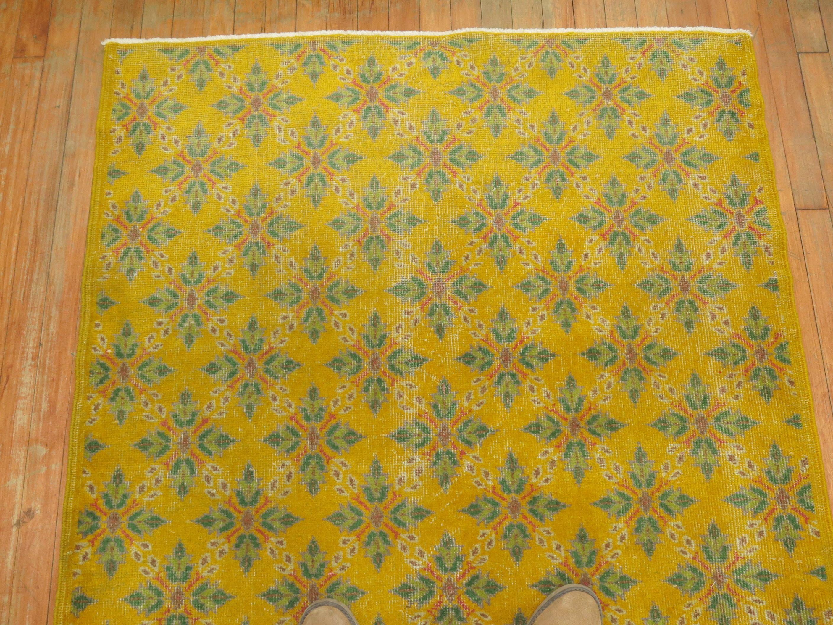 Alfombra turca de Anatolia con campo amarillo, acentos en rosa y verde.