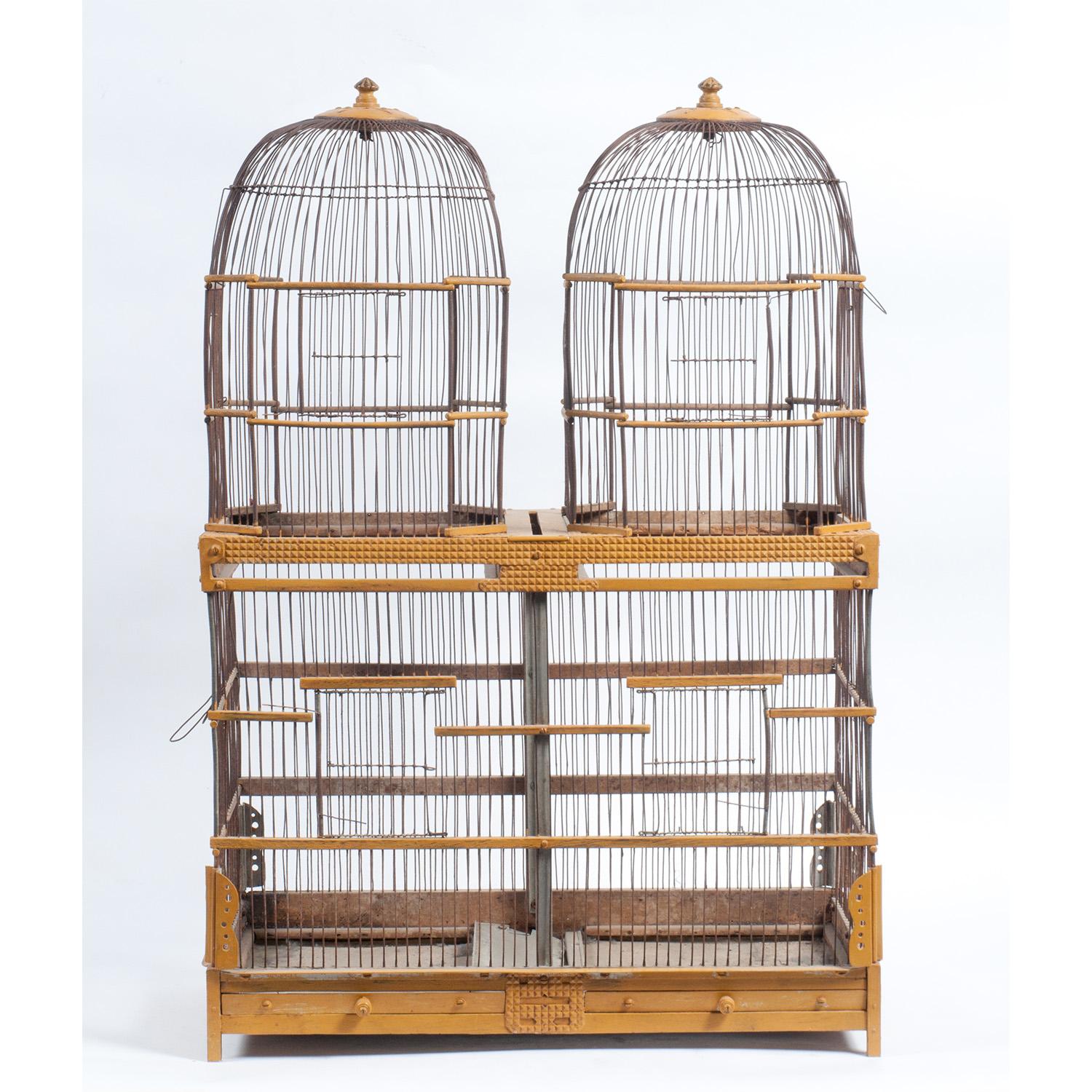 Vintage 19th Century yellow metal and wood double birdcage with matched domes, two drawers, and star detailing.
