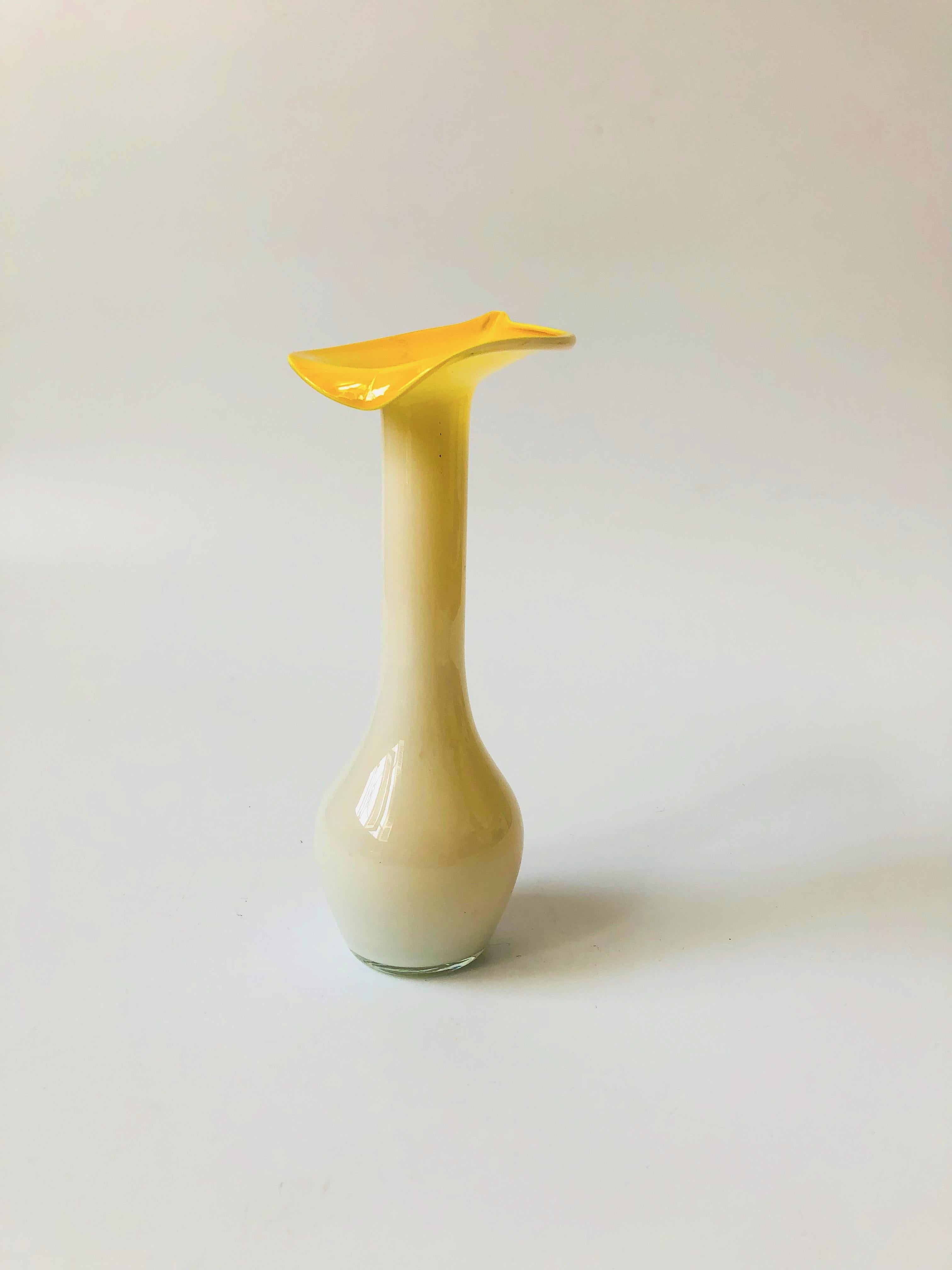 A beautiful vintage art glass vase in the shape of a lily. Lovely opaque white milk glass encases a bright yellow interior.
  