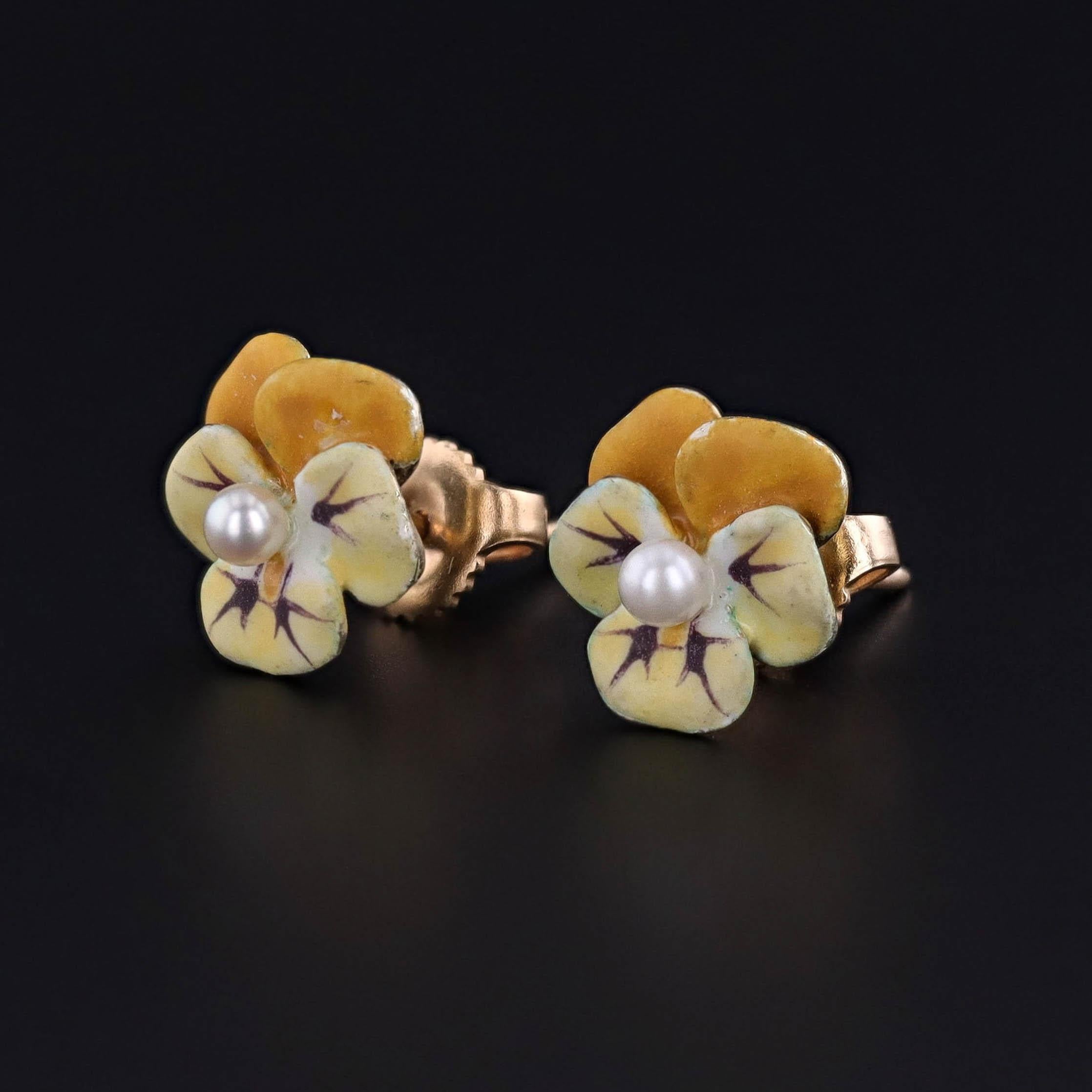 Charmantes et féminines, ces boucles d'oreilles vintage (circa 1950s) sont façonnées comme de délicates pensées en or 14k, leurs pétales richement décorés d'émail jaune et centrés par des perles lustrées. La pensée, un motif floral très apprécié en