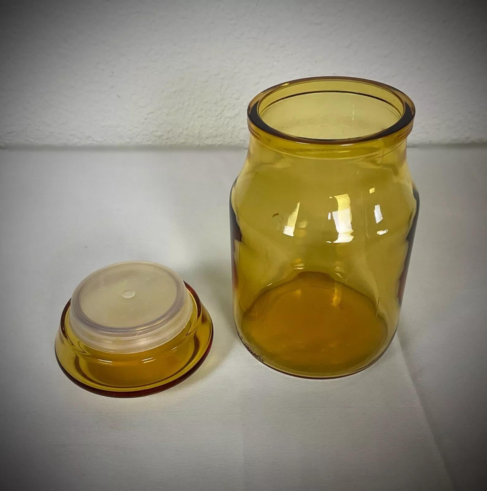 This vintage yellow glass bonbonnière, attributed to Maxwell, is a charming and functional decorative jar. Its vibrant translucent yellow hue gives it a striking mid-century aesthetic, making it a perfect addition to any vintage glassware