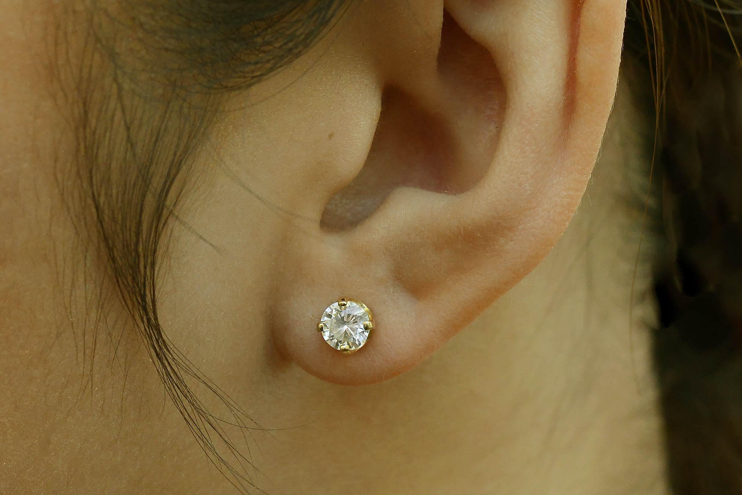 A pair of vintage diamond stud earrings. Totaling 1 carat, the round diamonds glisten a highly-desired near colorless (G color) graced with sparkling clarity and sit snugly in their 4 prong, 14k yellow gold settings, ensuring a dynamic, classic