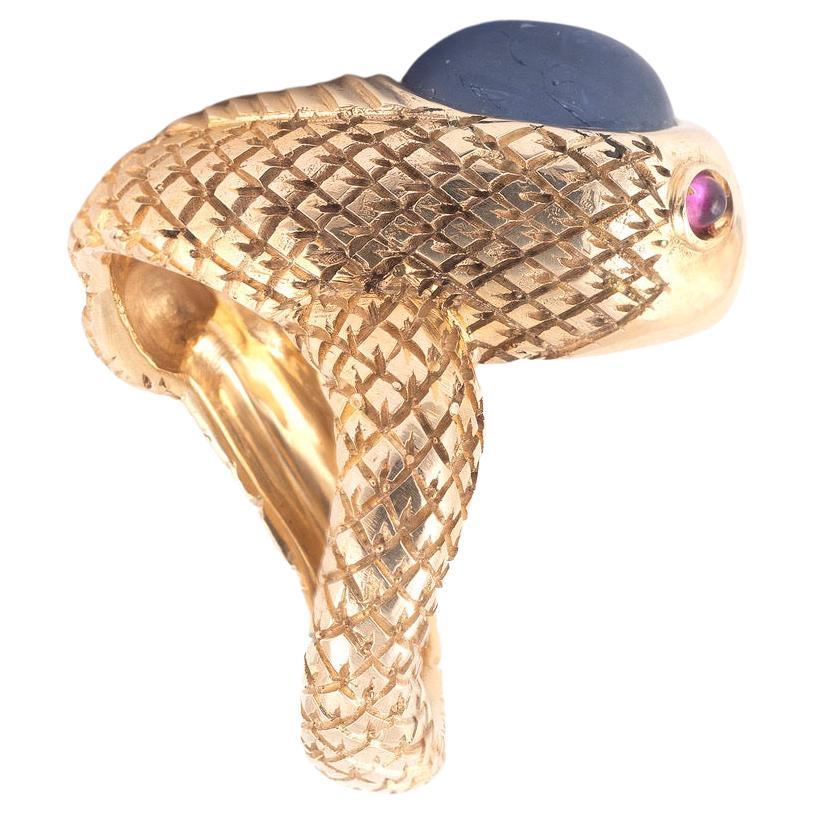 Realistically modelled as a snake, the coiled body engraved with snake-skin design, the head set with a cabochon sapphire approximately 6ct , the eyes with cabochon rubies
Size : 8
Gross weight: 21,67g.