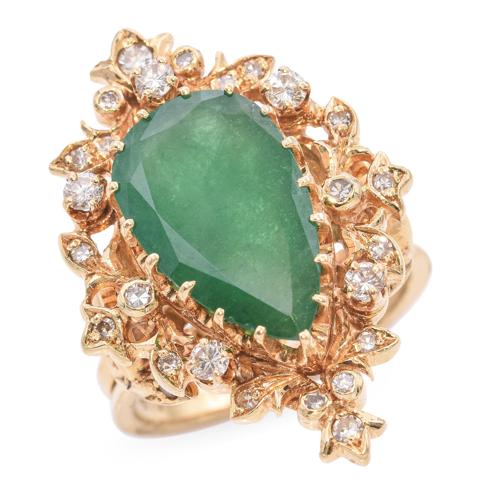 Cette bague vintage en or jaune présente une émeraude de couleur riche encadrée de diamants étincelants dans une monture ornementale inspirée de la nature. Le travail détaillé de l'or évoque des formes organiques, ce qui confère à la pièce un