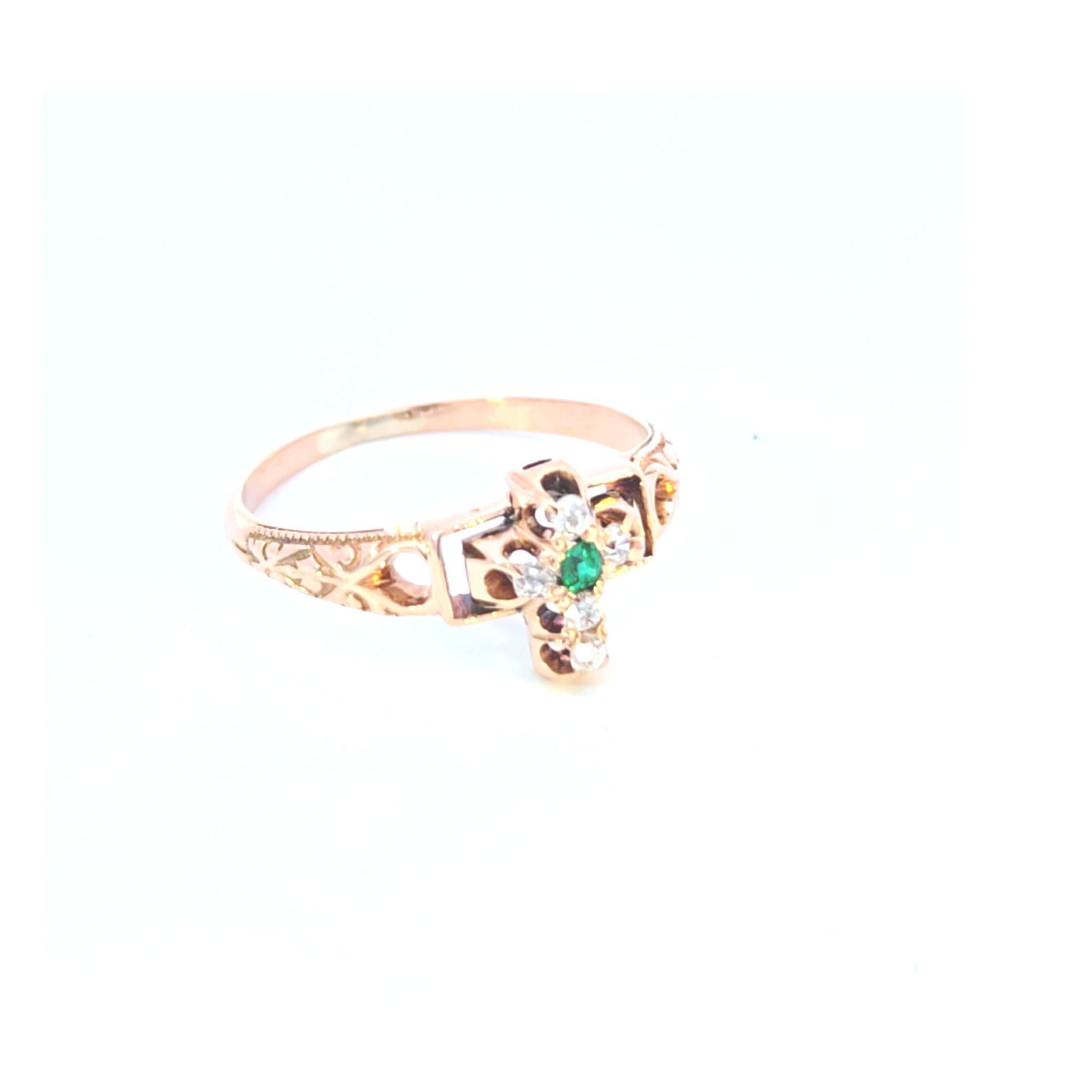 This beautiful vintage 14 karat yellow gold ring features a bright and lively emerald at the center of the cross, with accent diamonds.