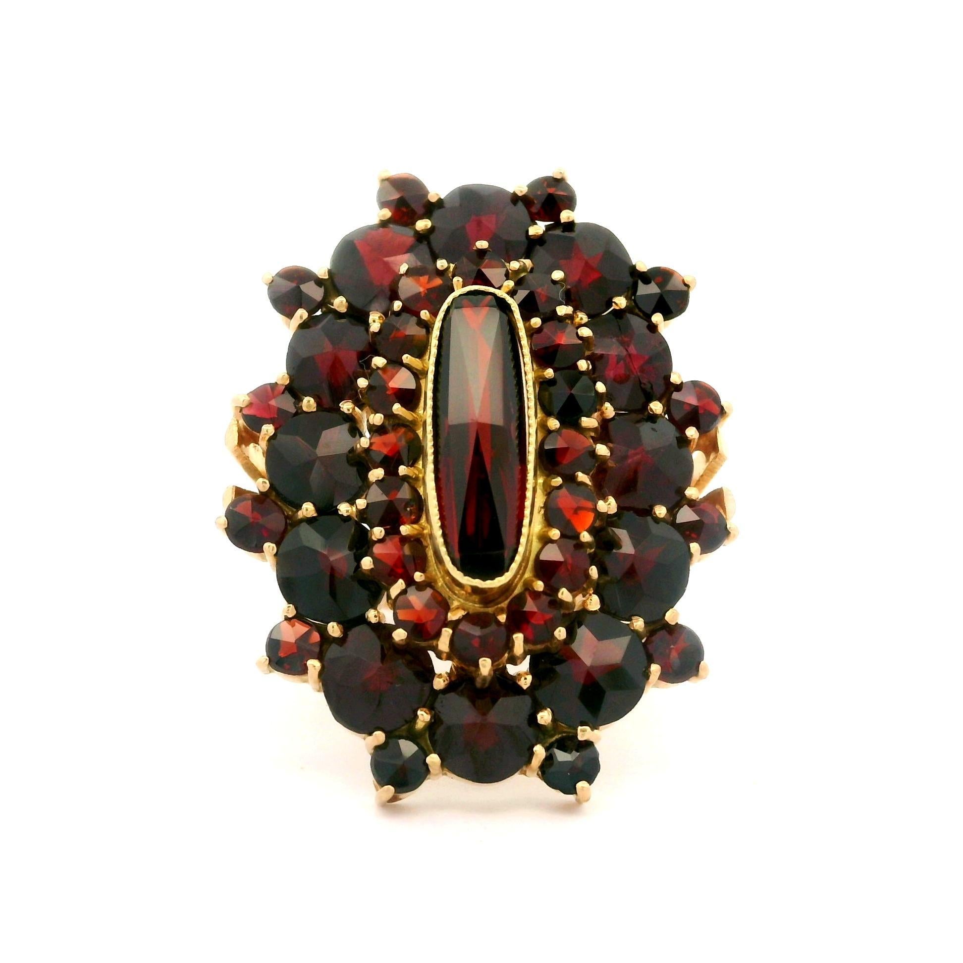 --Stone(s):--
Numerous Natural Genuine Garnets - Round & Elongated Cushion Shapes - Bezel & Prong Set - Great Dark Red Colors

Material: Solid 14K Yellow Gold
Weight: 9.2 Grams
Ring Size: 10.5 (Fitted on a finger. We can custom size this ring.