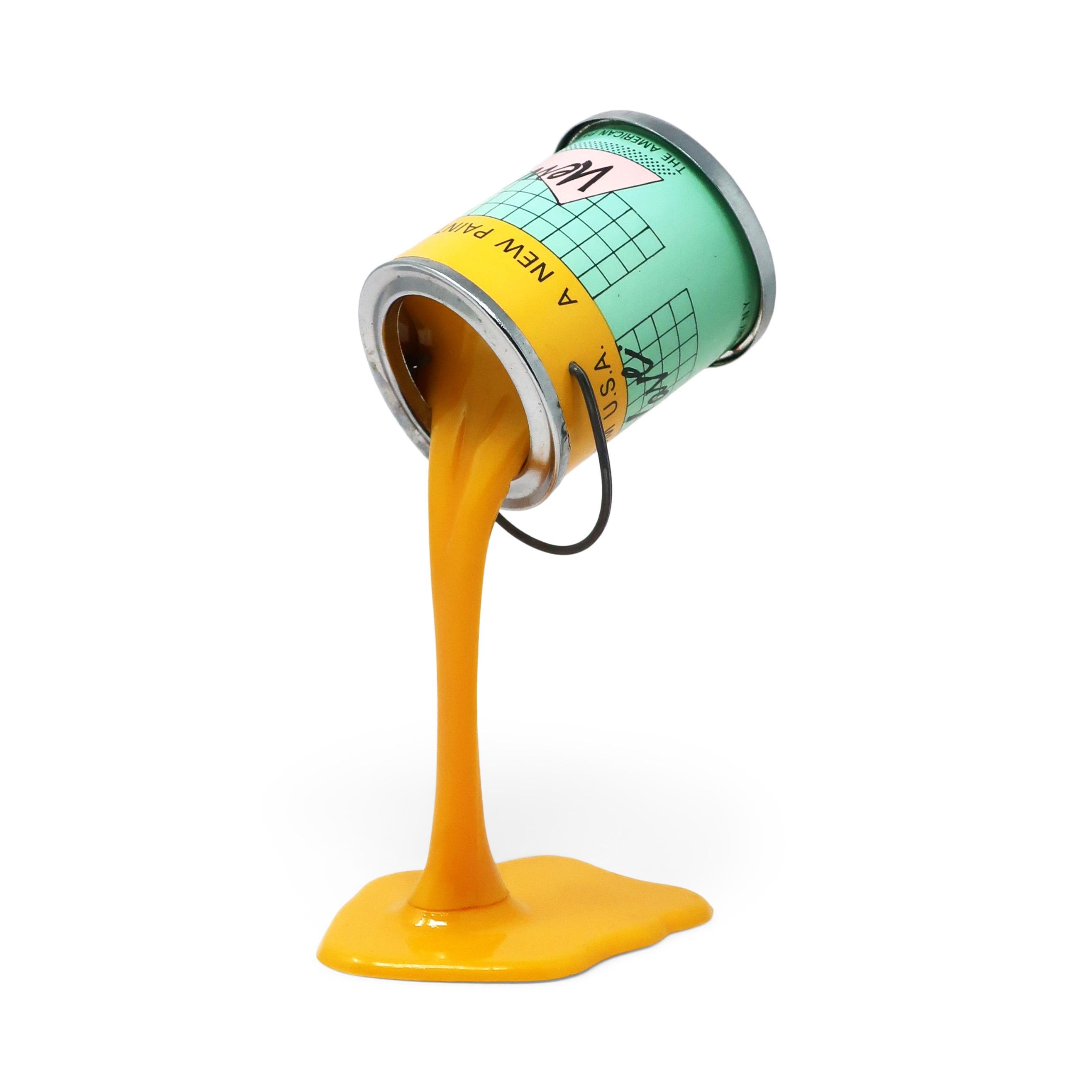 A perfectly Pop Art 1980s pouring paint can piggy bank/sculpture.  Metal paint can with a quarter-sized coin slot in its bottom appears to be defying gravity by resting on a pouring stream of paint.  Came in three colors and this is the yellow paint